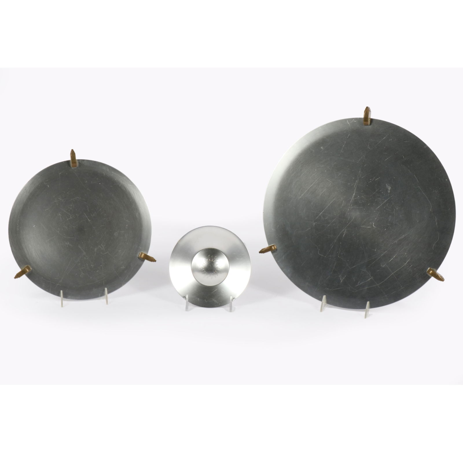 Kensington Lurelle Guild 2 Aluminum/Brass Footed Platters; Ashtray 16" Diam. (Largest): Kensington Lurelle Guild 2 Aluminum/Brass Footed Platters; Ashtray Two 1938 #7105 12" and 16" "Aztec" or "Cortez" Footed Platters; and #7416 "Corona" Ashtray. Provenance: Charles Alexander, Indianapol