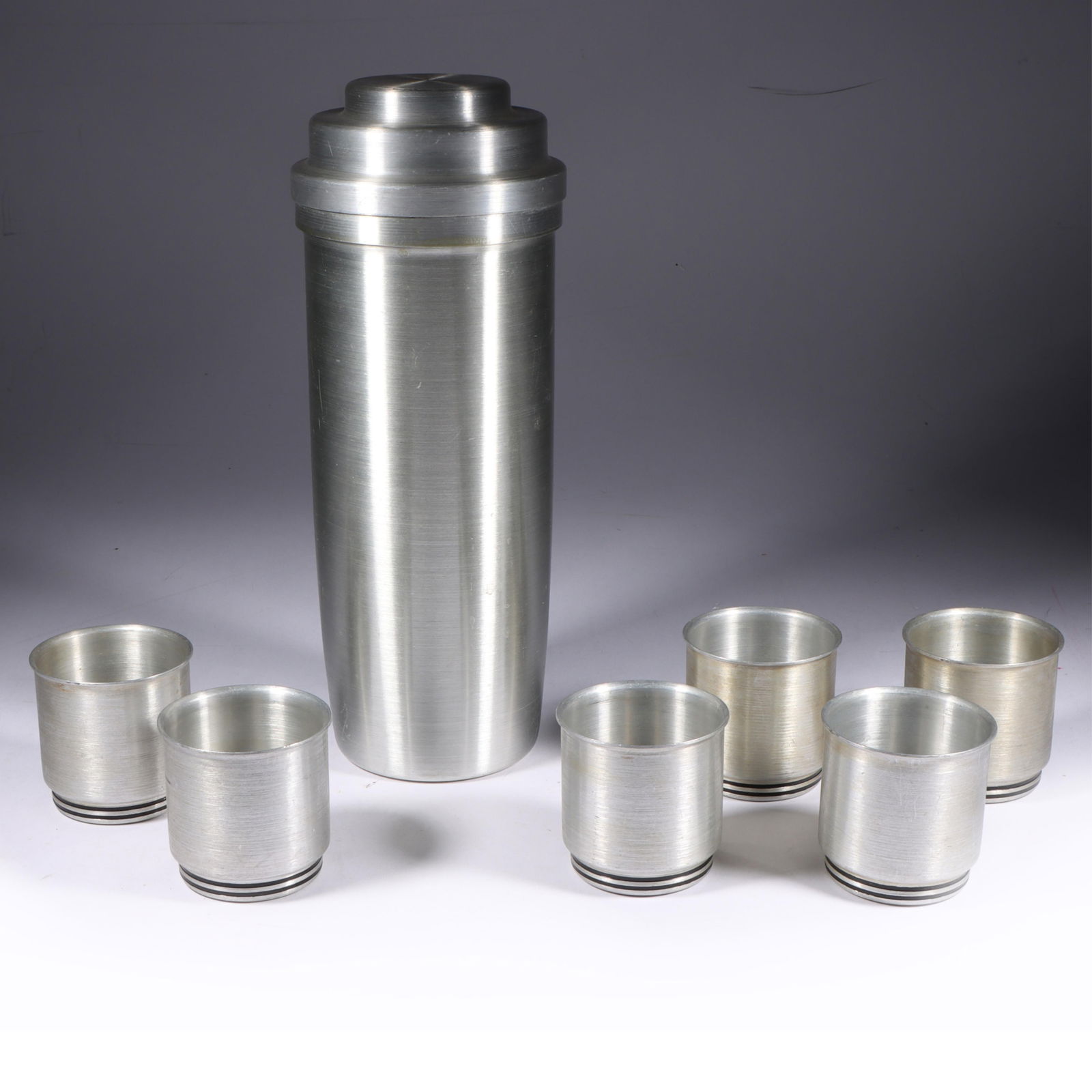 Art Deco Spun Aluminum Cocktail Shaker w/ six West Bend Cocktail Cups 11"H x 4"Diam. (shaker): Art Deco Spun Aluminum Cocktail Shaker w/ six West Bend Cocktail Cups Unmarked Spun Aluminum Cocktail Shaker has original retaining spring inside two piece lid; includes six cocktail cups marked "WB"