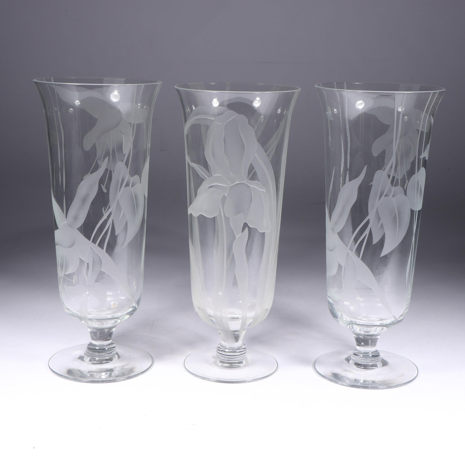 Three Dorothy Thorpe Etched Glass Vases 10"H x 4"Diam. (one): Three Dorothy Thorpe Etched Glass Vases Etched Iris design on single; Etched Orchid design on pair. All marked w/Monogram: DTC. Provenance: Charles Alexander, Indianapolis, IN 10"H x 4"Diam. (one)