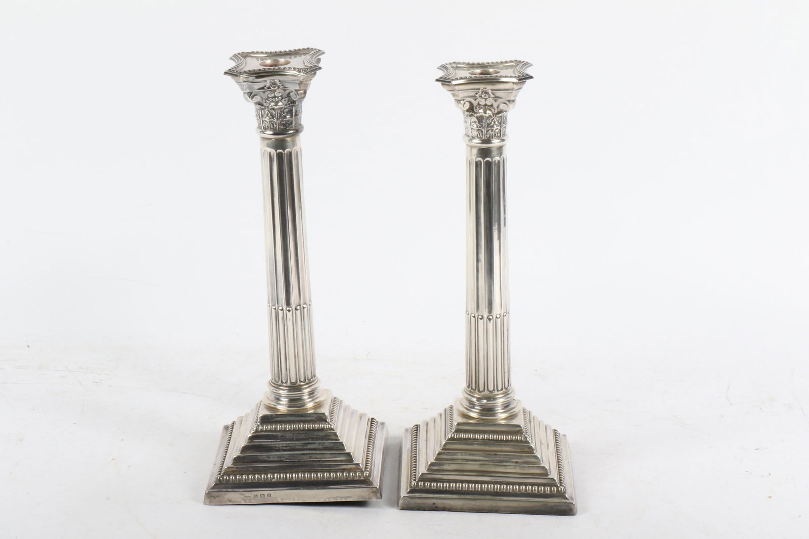 Pair Henry Griffith & Sons English sterling silver Neoclassical Corinthian column candlesticks,: Pair Henry Griffith & Sons English sterling silver Neoclassical Corinthian column candlesticks, early 20th Century. HG&S, Birmingham. Cement filled. One has warping to the underside covering. 12 1/4"H