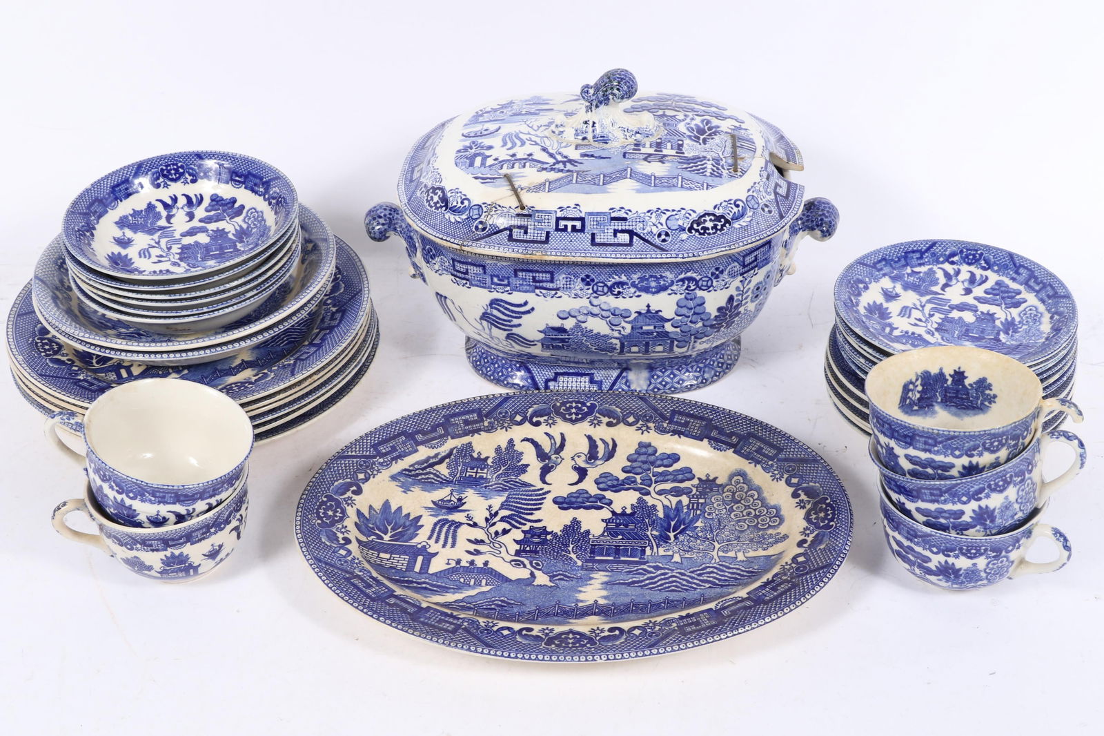 Vintage Blue Willow Japan porcelain dinnerware, 31pc: soup tureen, 6 dinner plates, 2 soup bowls, 6: Vintage Blue Willow Japan porcelain dinnerware, 31pc: soup tureen, 6 dinner plates, 2 soup bowls, 6 fruit bowls, 5 bread plates, platter, 5 cups and 6 saucers One cup has a broken handle. Soup tureen