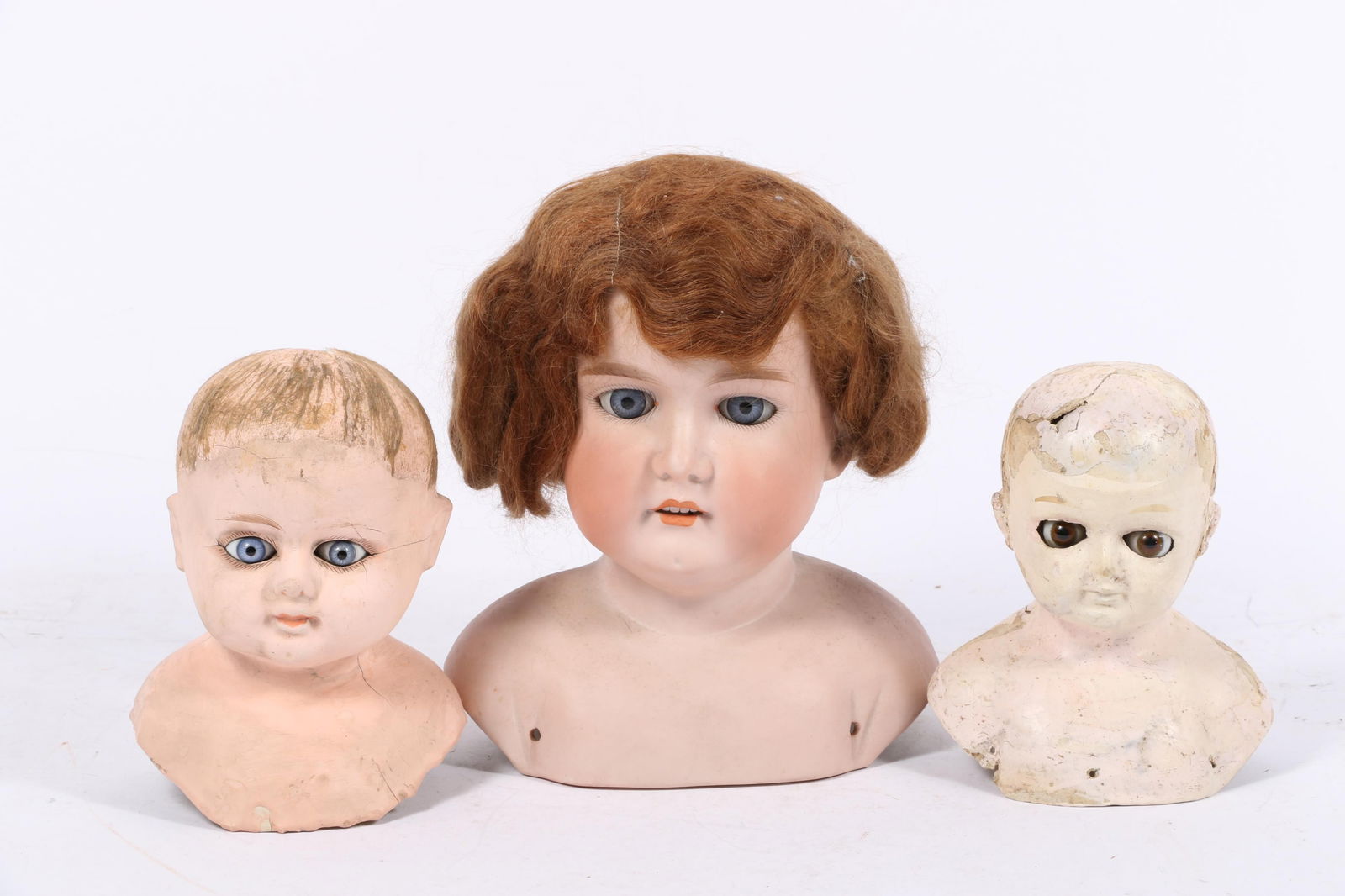 Three vintage / antique doll heads: 2 paper mache composition doll heads with glass eyes, German: Three vintage / antique doll heads: 2 paper mache composition doll heads with glass eyes, German bisque doll head with sleep eyes 9"H x 7"W x 3 1/2"D (Largest)