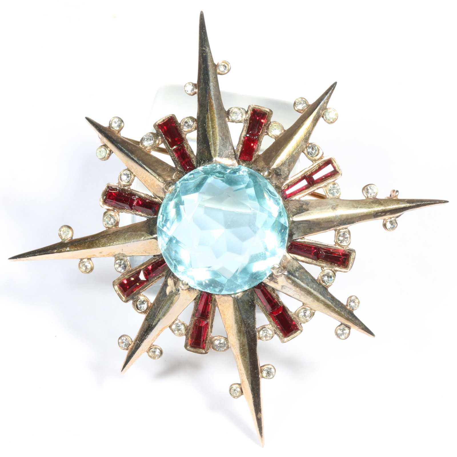 Crown Trifari 1944 sterling silver vermeil starburst brooch with large aqua jewel center and red: Crown Trifari 1944 sterling silver vermeil starburst brooch with large aqua jewel center and red baguette rhinestones. 2 3/4"H x 2 3/4"W