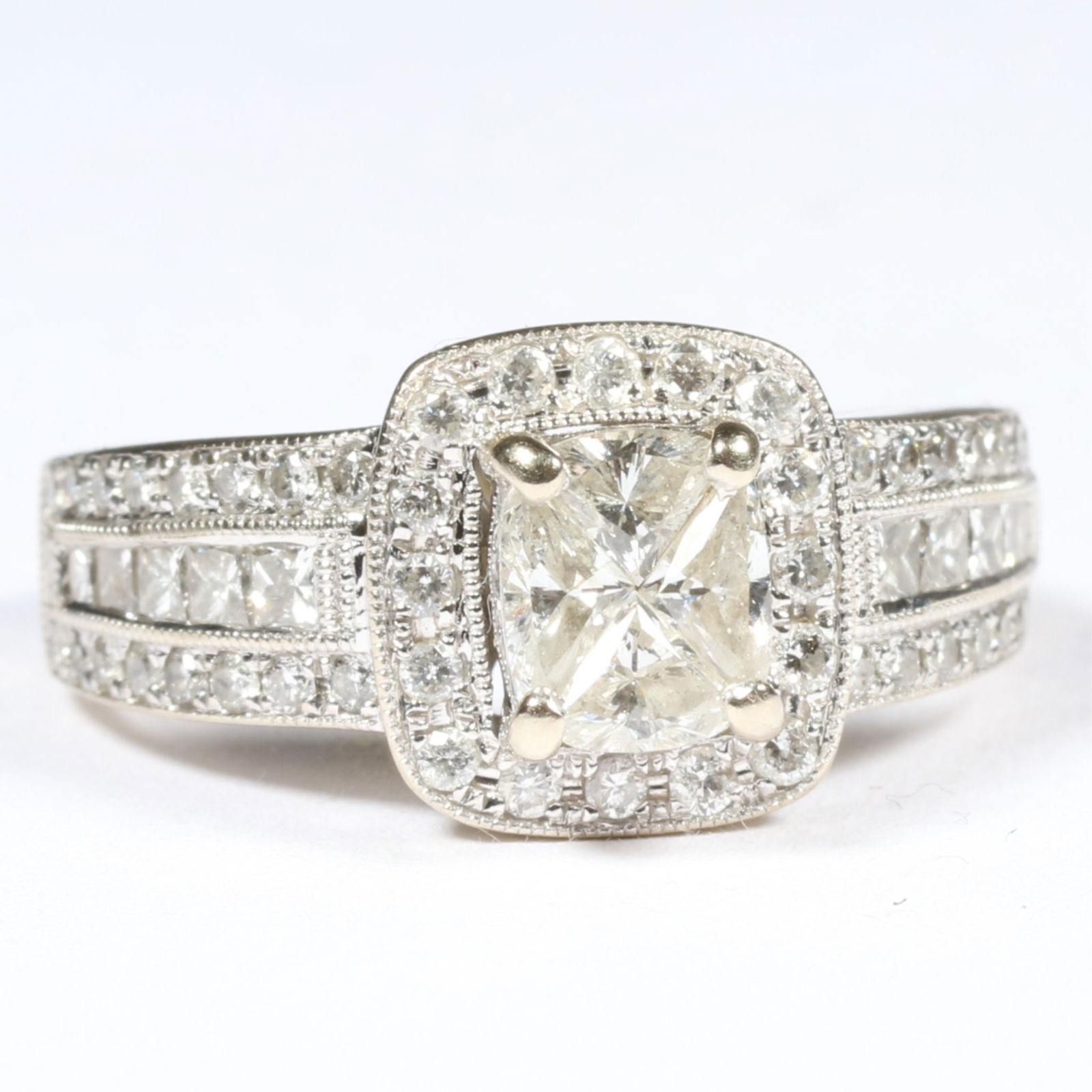 14K white gold tiered engagement ring with four trillion cut diamonds in center surrounded by halo: 14K white gold tiered engagement ring with four trillion cut diamonds in center surrounded by halo of full cut round diamonds with round and square cut diamond shank. 1. total carat weight 4 center I-