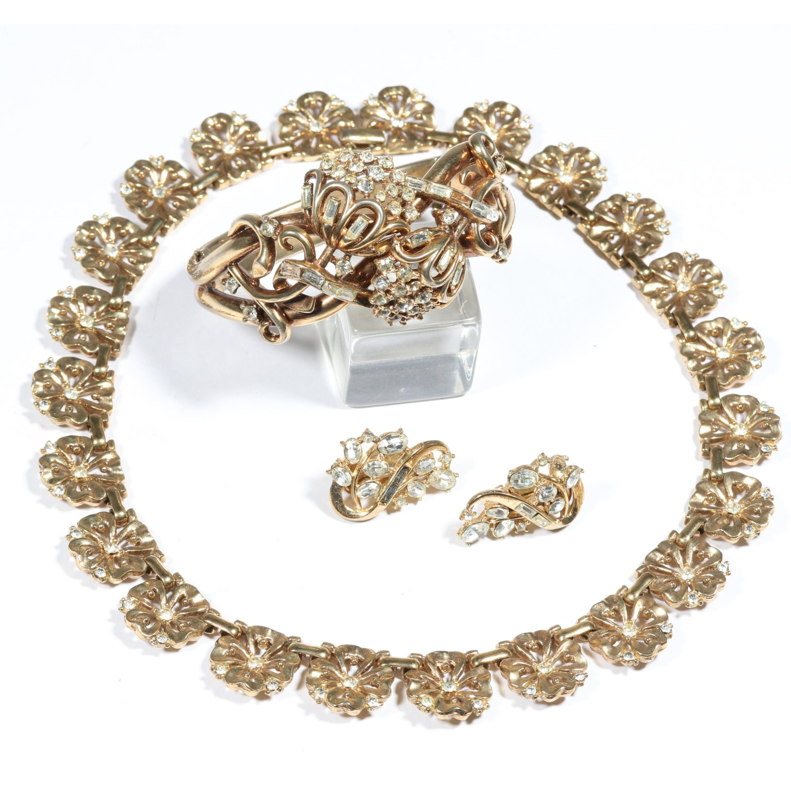 Crown Trifari Retro floral rhinestone necklace, rhinestone clamper bracelet, and earrings. 1 3/8"H x: Crown Trifari Retro floral rhinestone necklace, rhinestone clamper bracelet, and earrings. Some missing stones on bracelet and earrings Provenance: From the collection of Cheryl Killmer. 1 3/8"H x 2 1