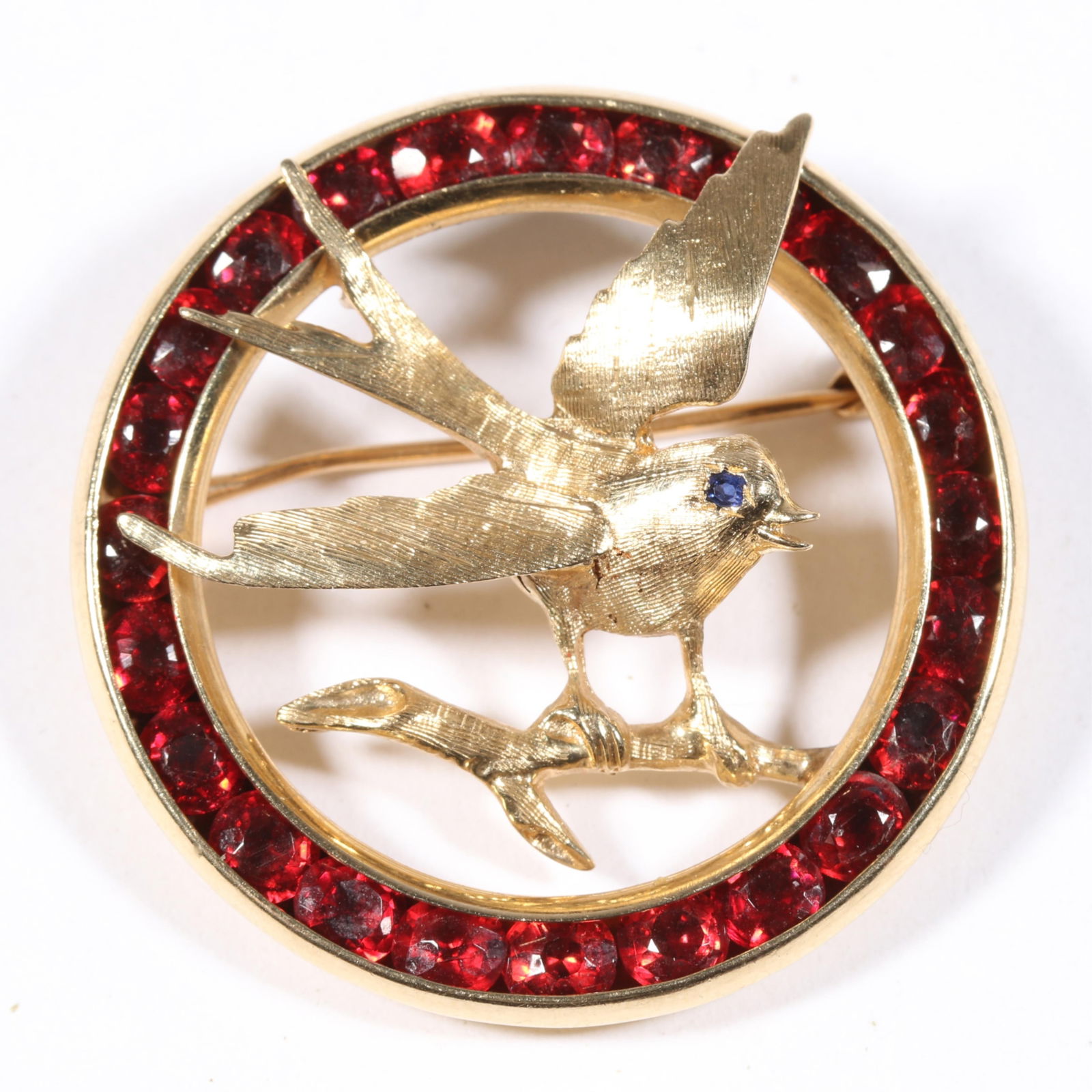 14K yellow gold bird brooch with garnet gemstone halo. 1 3/8"Diameter: 14K yellow gold bird brooch with garnet gemstone halo. 6.900DWT The purchase of gold requires confirmed funds. 1 3/8"Diameter