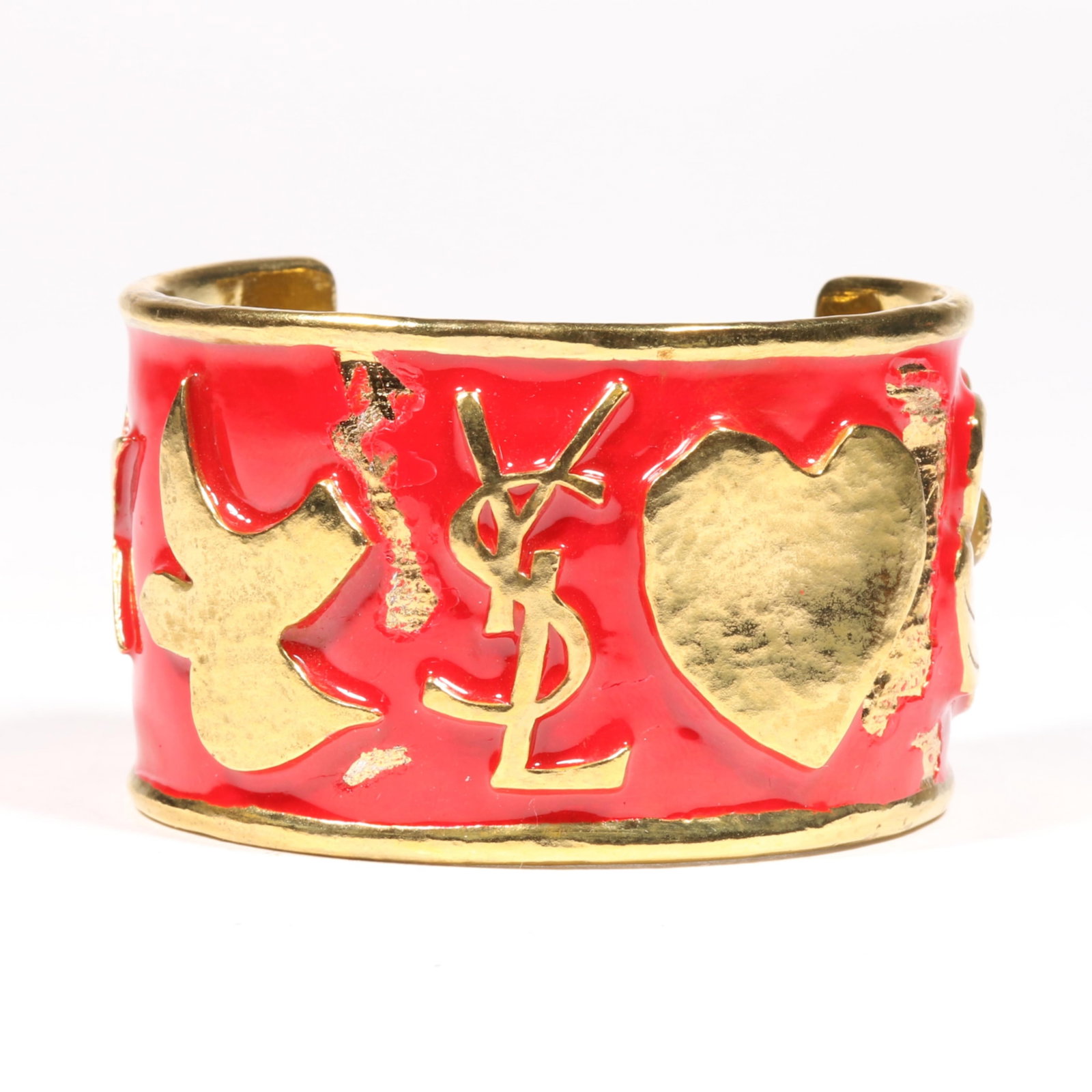 Yves Saint Laurent YSL gold tone and red enamel logo cuff bracelet, heart, dove, star, flower 1: Yves Saint Laurent YSL gold tone and red enamel logo cuff bracelet, heart, dove, star, flower Damage to enamel Provenance: From the Collection of Joan Duran 1 1/2"H x 2 3/8"Diam.