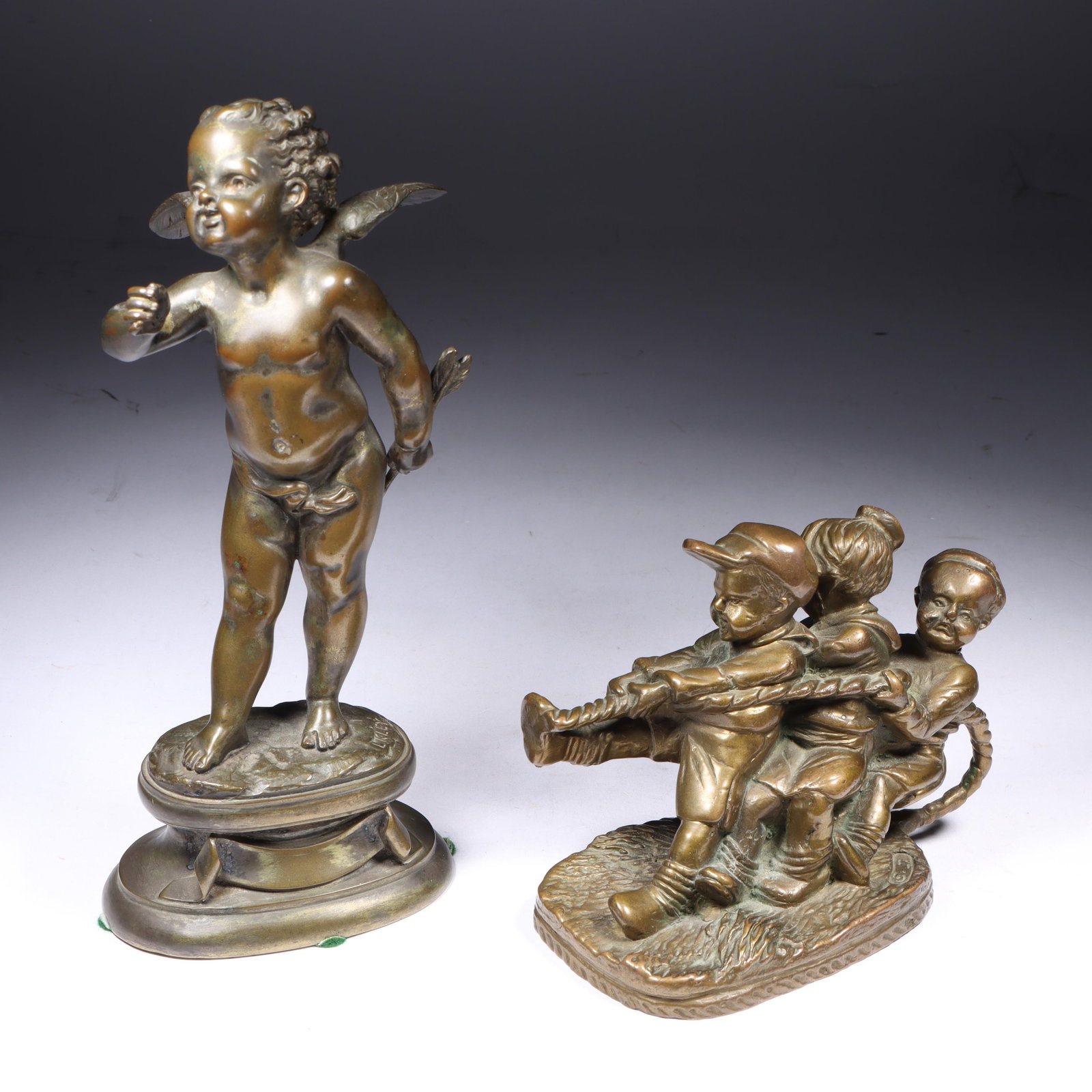 Two bronze cabinet sculptures; Cupid putto statuette by Louis Kley, and tug-of-war playing children: Two bronze cabinet sculptures; Cupid putto statuette by Louis Kley, and tug-of-war playing children figure group signed S.J. Both marked to base. 8 1/4"H x 4"W (putto measured)
