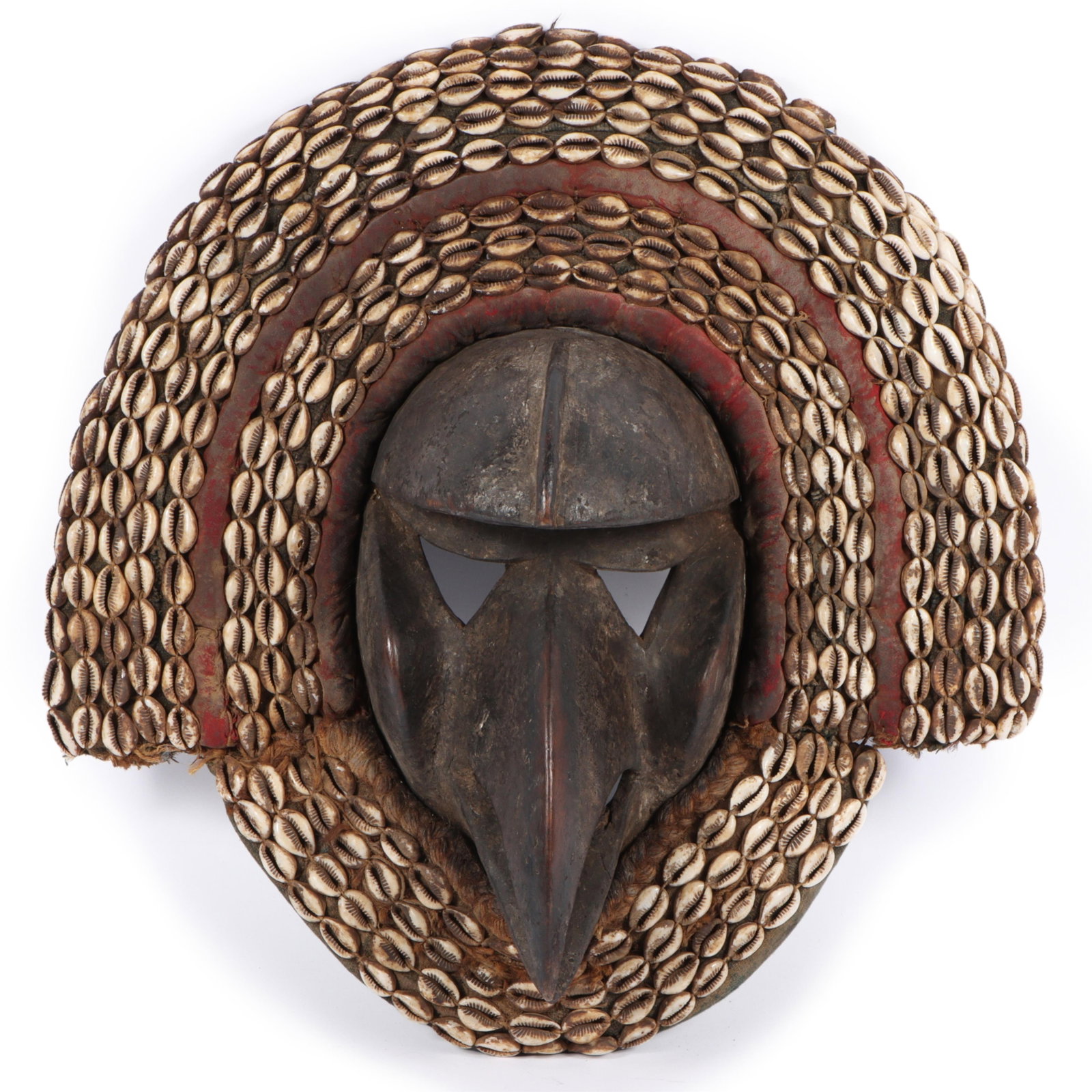African tribal Dan Koma Su carved ceremonial bird face mask 17"H x 16 1/2"W: African tribal Dan Koma Su carved ceremonial bird face mask featuring a prominent elongated beak-like nose and adorned with rows of cowrie shells. 17"H x 16 1/2"W