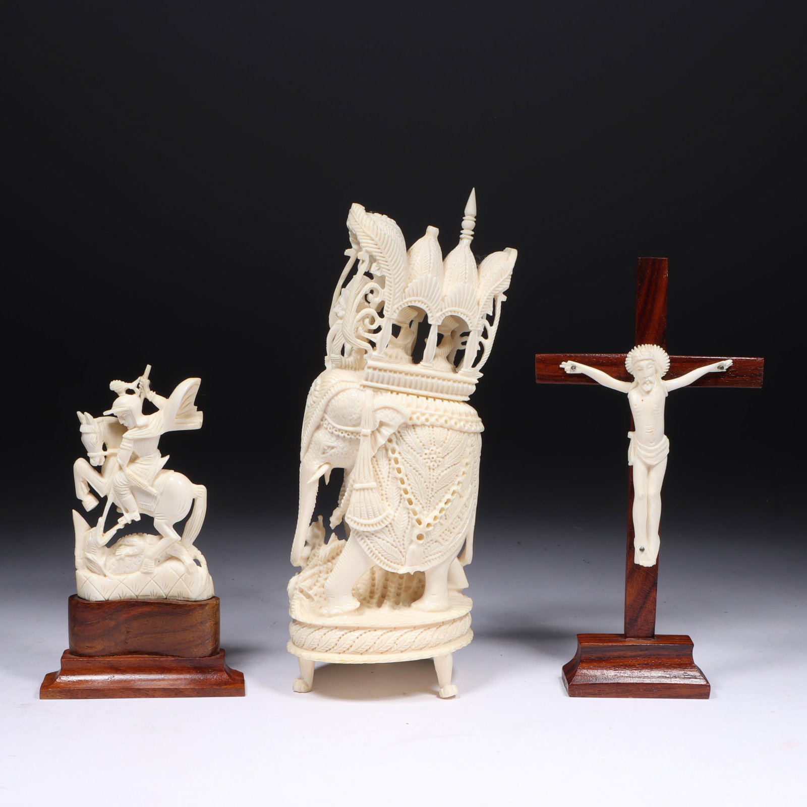 Three Antique Indian carved bone statuette sculptures: Christ on wooden crucifix, St. George slaying: Three Antique Indian carved bone statuette sculptures: Christ on wooden crucifix, St. George slaying the dragon mounted on wooden base, elephant carrying a howdah piece from howdah is broken 7"H x 2 3