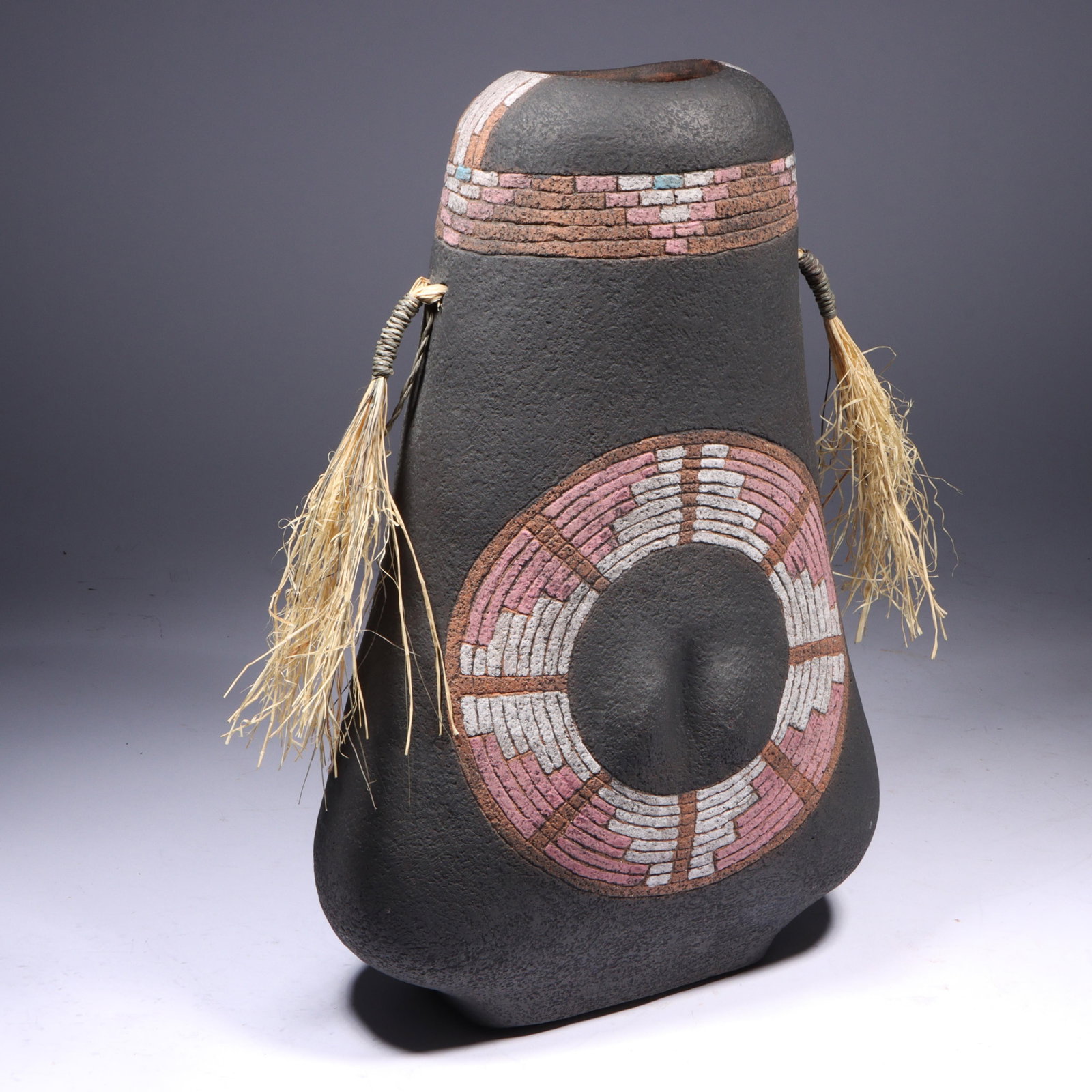 Michael Janes (20th century) Southwestern polychrome pottery vase with etched geometric design and: Michael Janes (20th century) Southwestern polychrome pottery vase with etched geometric design and raffia tassels, 1988 Incised signature and date under base. 16"H x 11"W