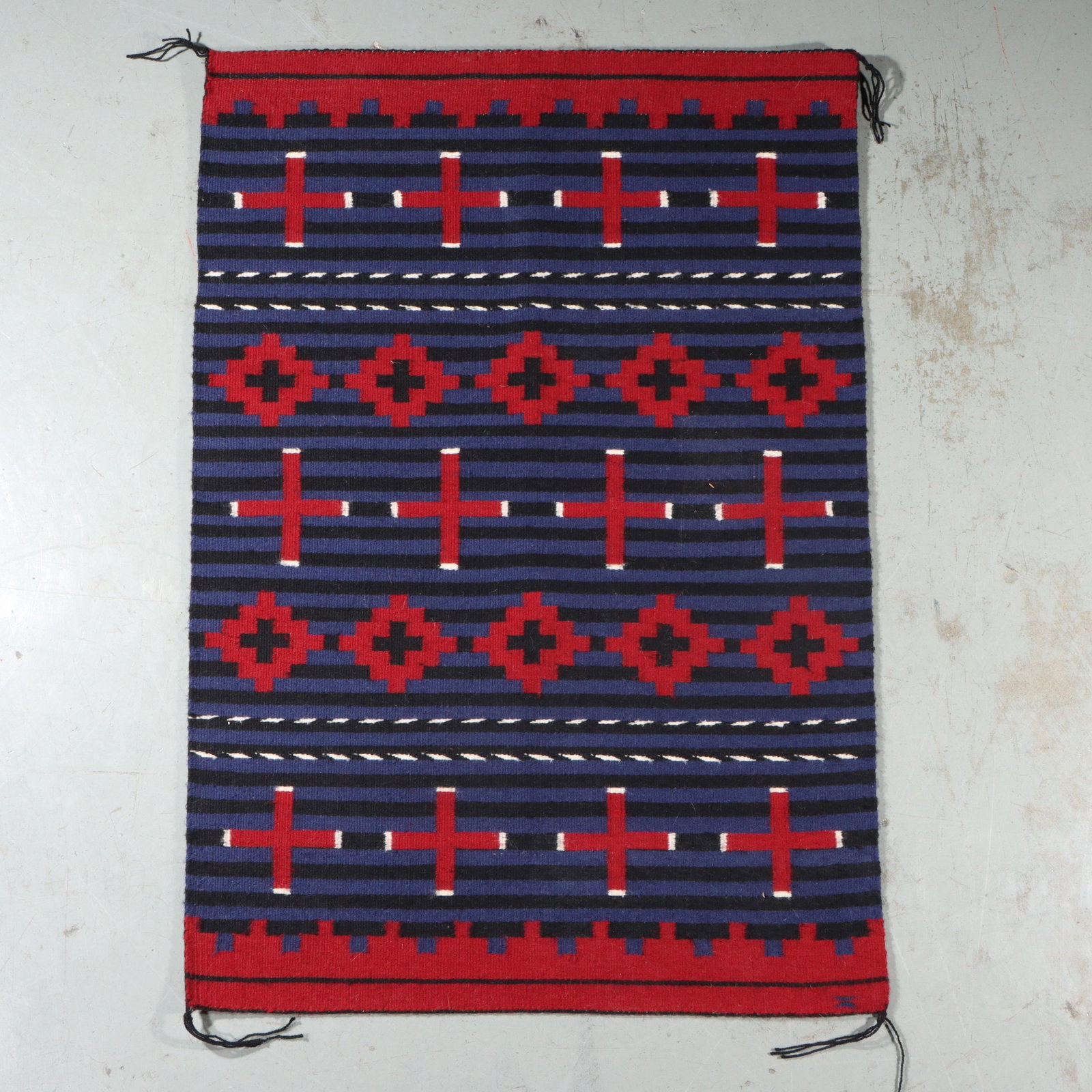 Navajo Native American Southwestern blanket rug weaving with alternating bands of crosses and: Navajo Native American Southwestern blanket rug weaving with alternating bands of crosses and diamonds This is a handwoven textile featuring a geometric pattern in red, blue, black, and white. 34 1/2"
