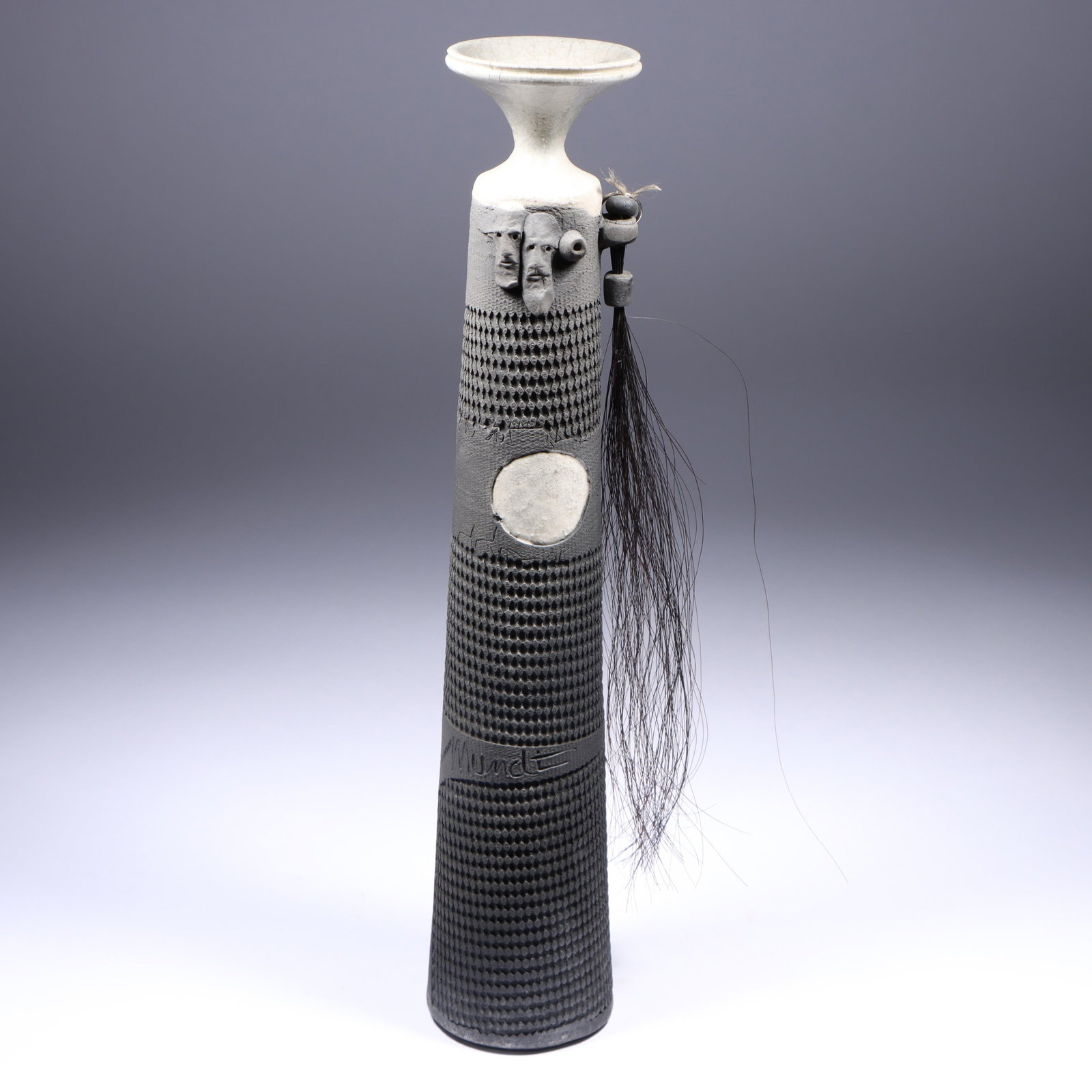 Phil Mundt (1933-2015) studio art pottery pit fired raku vase with applied faces and horse hair: Phil Mundt (1933-2015) studio art pottery pit fired raku vase with applied faces and horse hair tassel Incised signature 15 1/2"H x 3 3/4"Diam.
