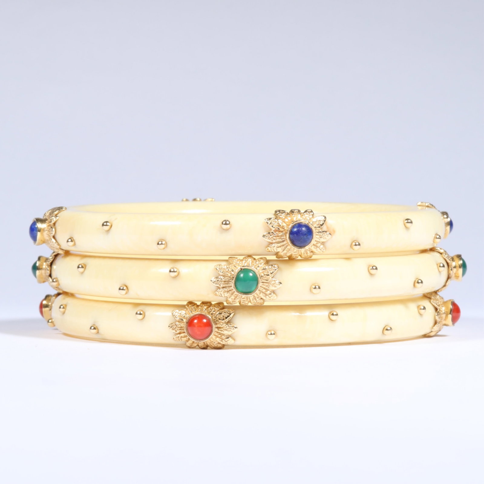 Set of three 14K Yellow Gold and Bone Vintage Bangle Bracelets with Floral Cabochon Accents in Lapis: Set of three 14K Yellow Gold and Bone Vintage Bangle Bracelets with Floral Cabochon Accents in Lapis Lazuli, Coral, and Emerald The three bracelets weigh 40.25dwt. total The purchase of gold requires 