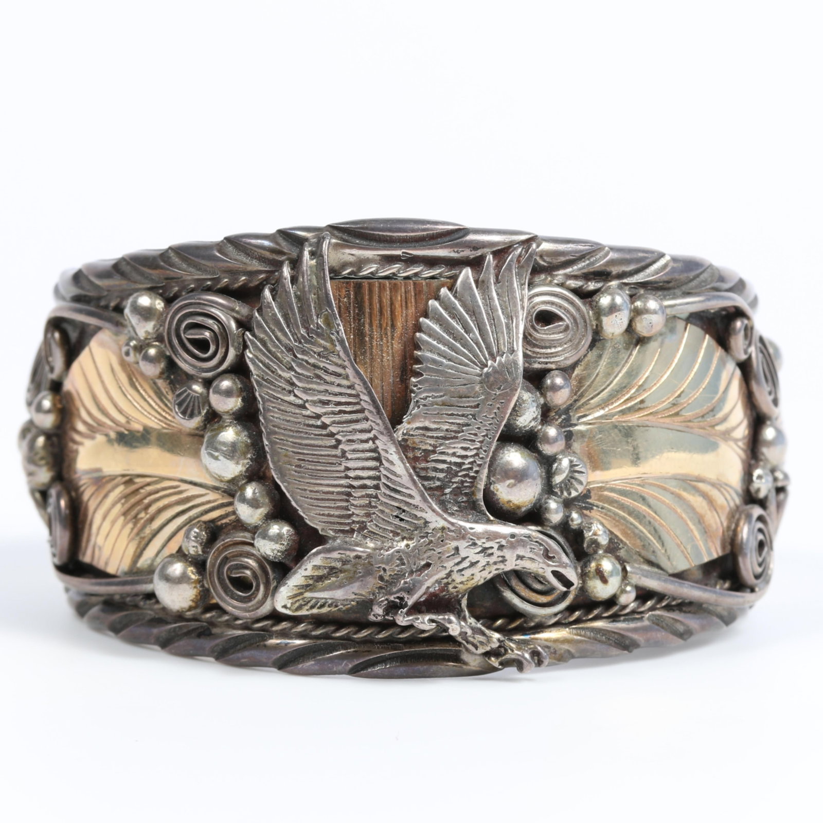 Vintage Native American Navajo or Zuni sterling silver cuff bracelet with detailed center eagle,: Vintage Native American Navajo or Zuni sterling silver cuff bracelet with detailed center eagle, fans, swirling stems, raindrops and gold filled leaves, unmarked 1 1/2"H x 2 1/4"Inner Diam.