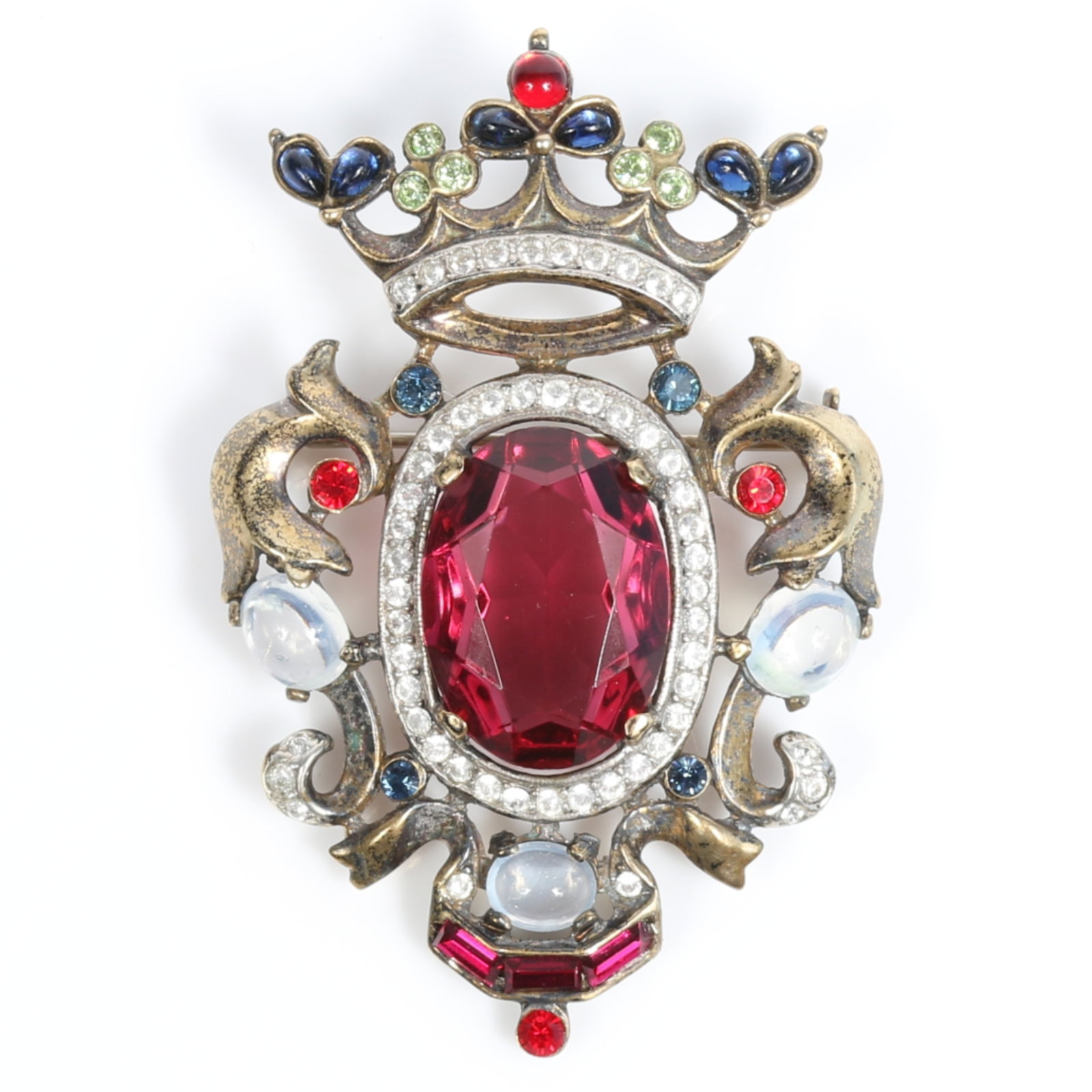 Trifari sterling vermeil royal crest jeweled crown brooch with large ruby red center jewel,: Trifari sterling vermeil royal crest jeweled crown brooch with large ruby red center jewel, rhinestone crystals, and moonstone cabochons Provenance: From the private collection of Dr. Claudia Brodhead