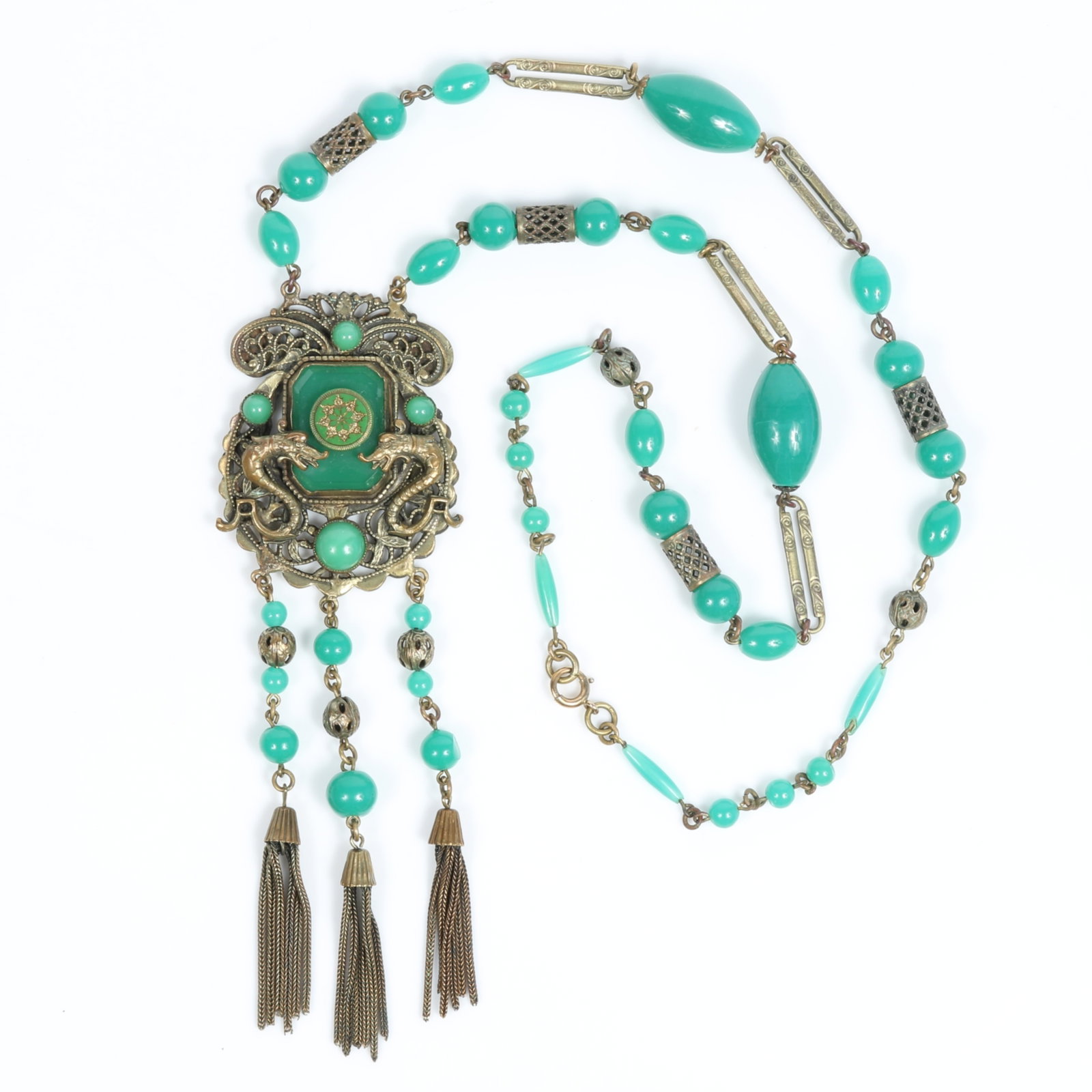 Long Czech glass green bead necklace with central dragon medallion and tassel fringe 24"L x 5" Drop: Long Czech glass green bead necklace with central dragon medallion and tassel fringe Provenance: From the private collection of Dr. Claudia Brodhead 24"L x 5" Drop