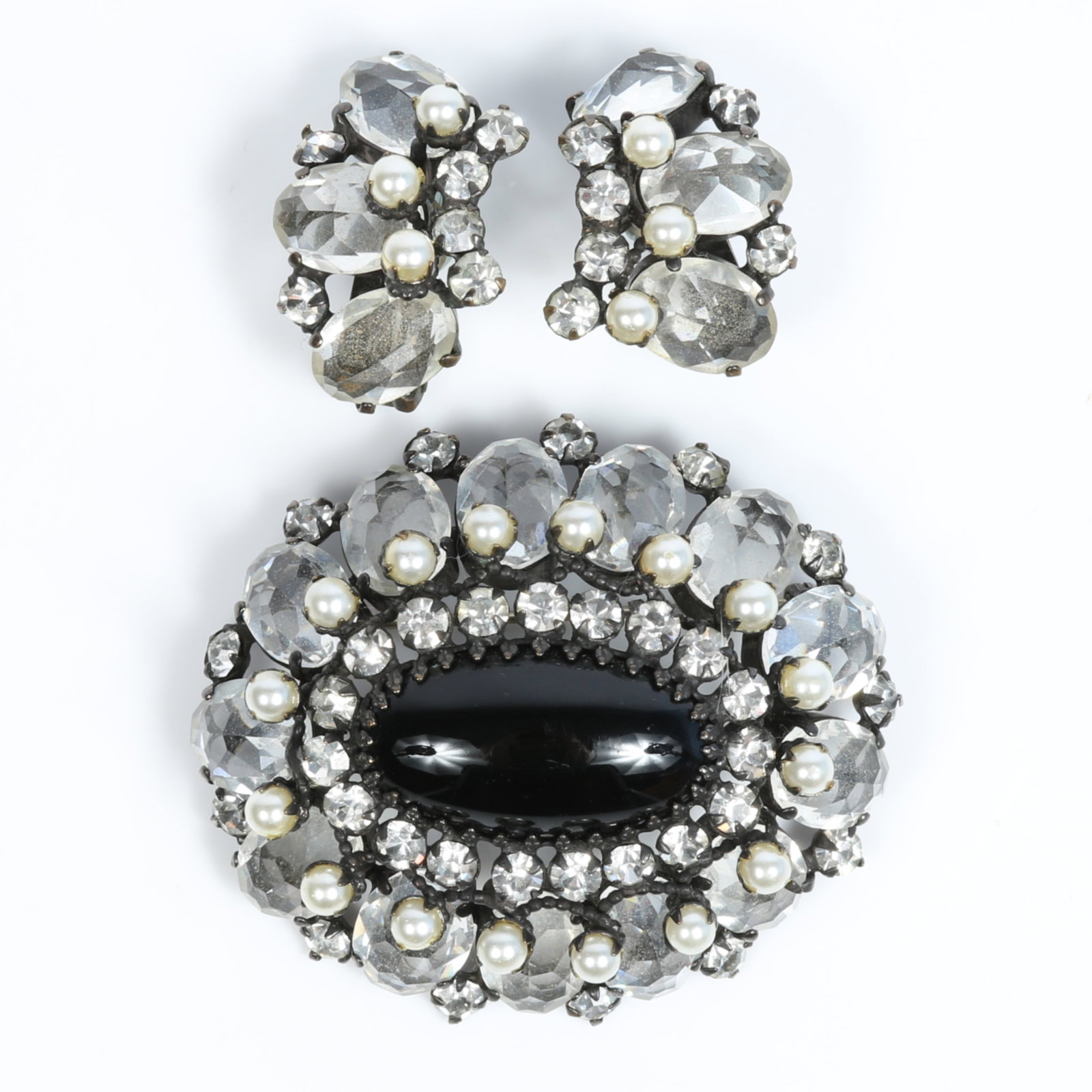 Schreiner large dimensional layered oval black cabochon brooch and matching earrings with unfoiled: Schreiner large dimensional layered oval black cabochon brooch and matching earrings with unfoiled clear rhinestone crystals and faux pearls, unsigned Provenance: From the private collection of Dr. Cl