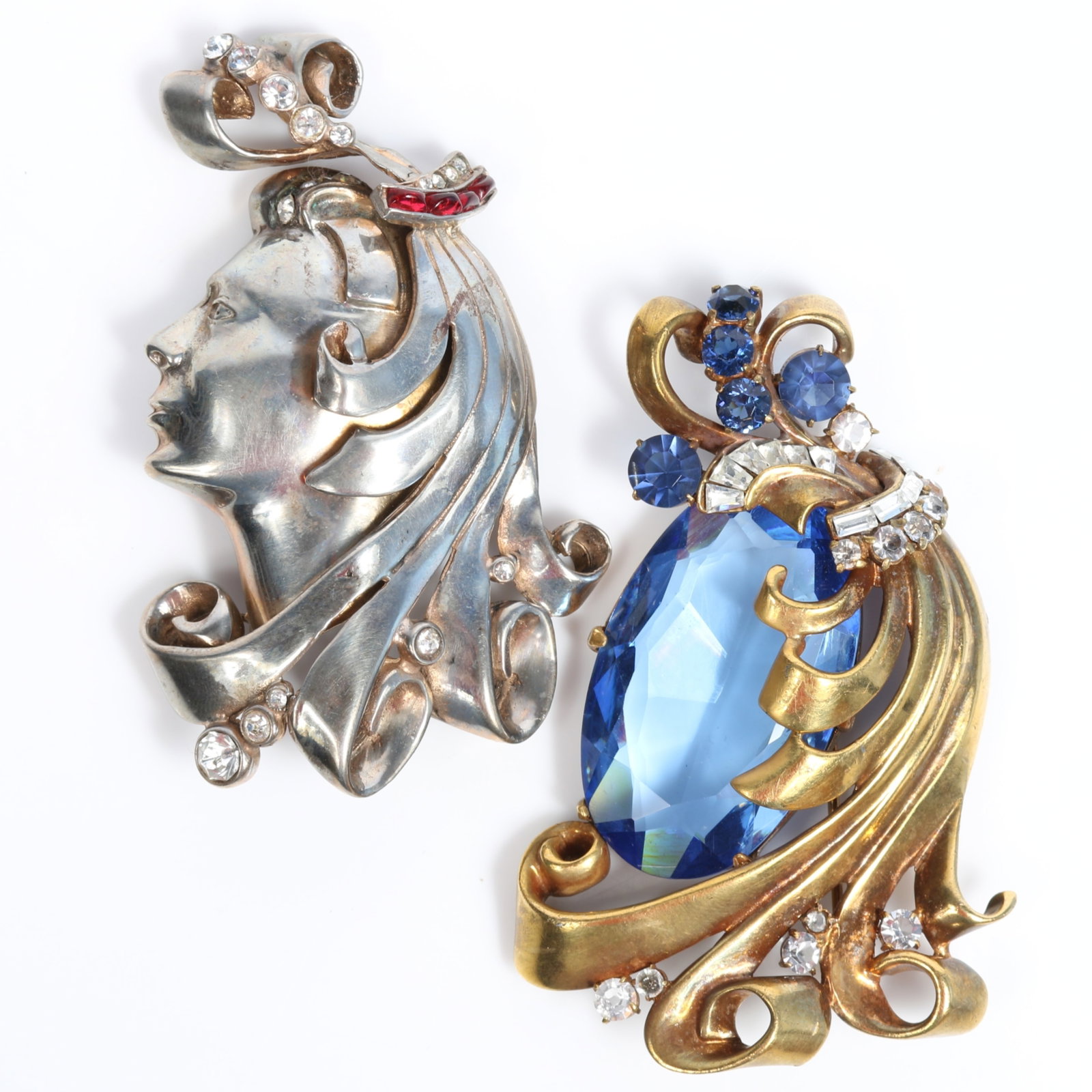 Pair of retro female head brooches one with large blue jewel accented with smaller various shaped: Pair of retro female head brooches one with large blue jewel accented with smaller various shaped stones and one with clear and ruby red rhinestones, book piece American Costume Jewelry Vol. 2 by Carl