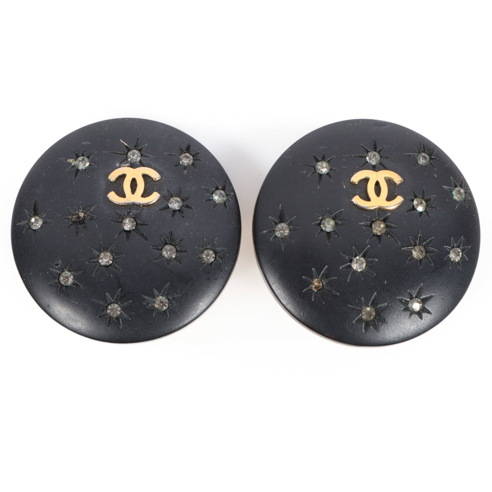 Pair of Chanel black star studded leather covered double CC logo button clip on earrings 1 1/2"Diam.: Pair of Chanel black star studded leather covered double CC logo button clip on earrings These pair of black earrings feature gold tone double C logos and rhinstone star accents. Two rhinestones are m