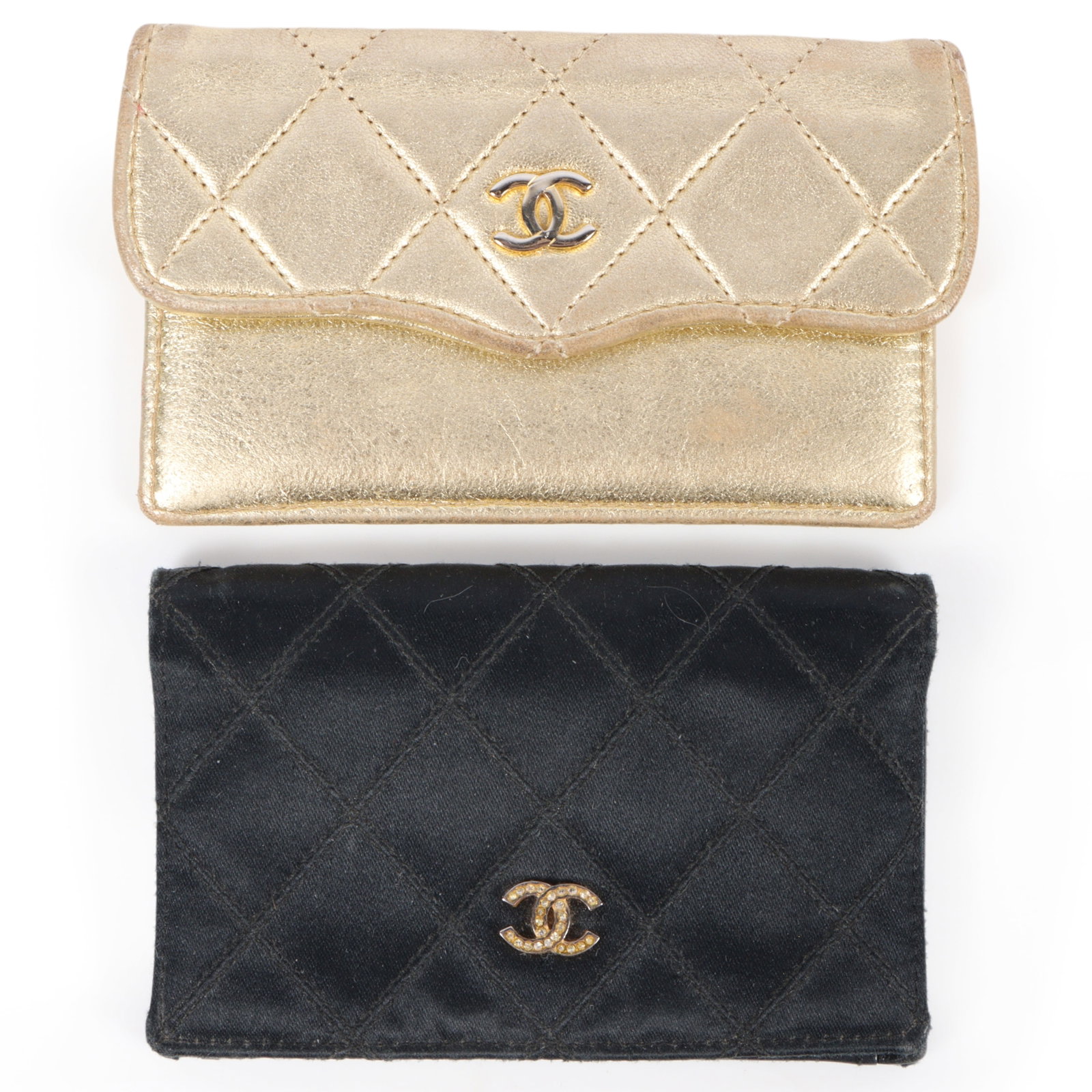 Pair of Chanel wallets including a black satin and leather wallet & a gold tone quilted leather: Pair of Chanel wallets including a black satin and leather wallet & a gold tone quilted leather wallet This pair features a black satin wallet with a leather interior and an exterior rhinestone CC emb