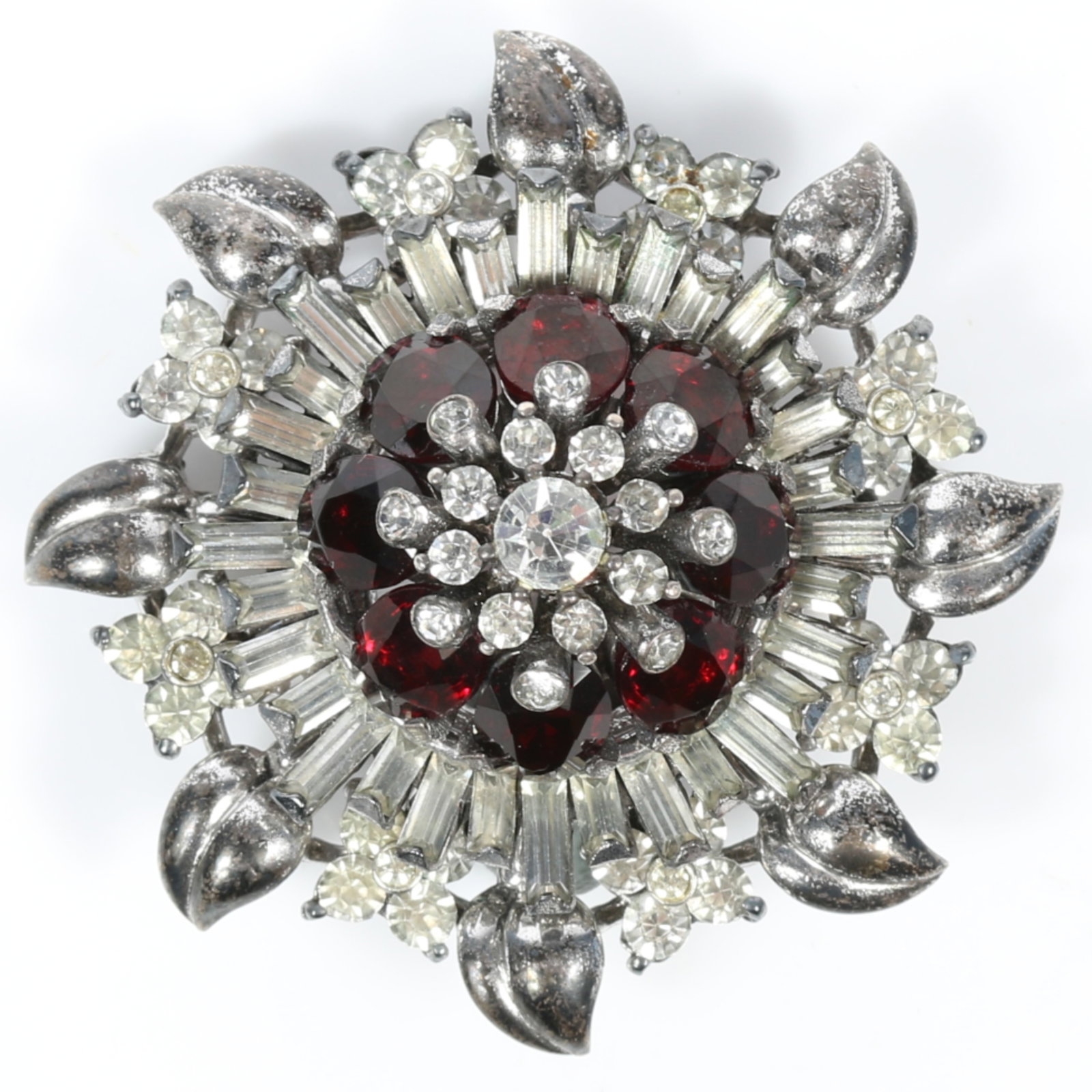 Pennino 1947 sterling silver dimensional sunburst book piece brooch with a cluster of ruby red: Pennino 1947 sterling silver dimensional sunburst book piece brooch with a cluster of ruby red stones surrounded by a radiant layer of clear baguette rhinestones. American Costume Jewelry Vol. 2 by Ca