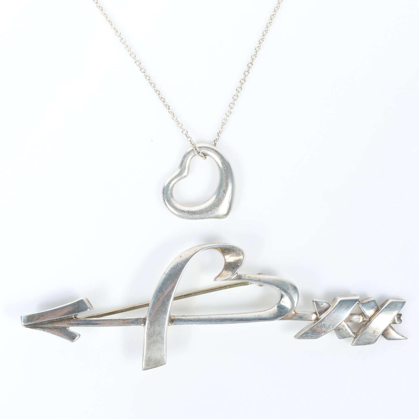 Tiffany & Co. 2pc sterling silver group: Paloma Picasso heart and arrow brooch with Elsa Peretti: Tiffany & Co. 2pc sterling silver group: Paloma Picasso heart and arrow brooch with Elsa Peretti open heart pendant necklace, both with original boxes and one pouch Provenance: From the Collection of 