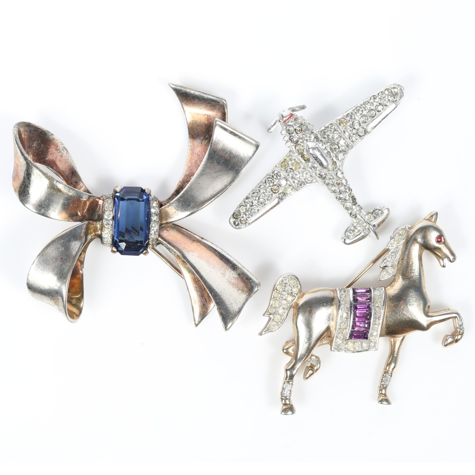 Trifari 3pc retro brooch group including sterling vermeil bow brooch with blue center stone and: Trifari 3pc retro brooch group including sterling vermeil bow brooch with blue center stone and diamante crystals, pave airplane, and prancing show horse with amethyst crystals and pave rhinestones 2"