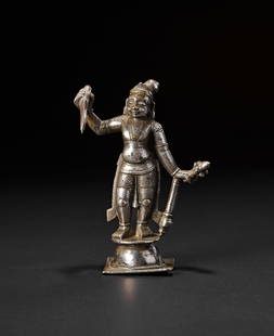 A SILVER OVERLAID BRONZE OR BRASS FIGURE OF A MALE DEITY, SOUTH INDIAN, 18TH CENTURY: The figure stands in a dynamic pose on a tiered base, holding a curved sword in one hand and a heavy mace in the other. The deity wears a conical headdress, earrings, and traditional attire with