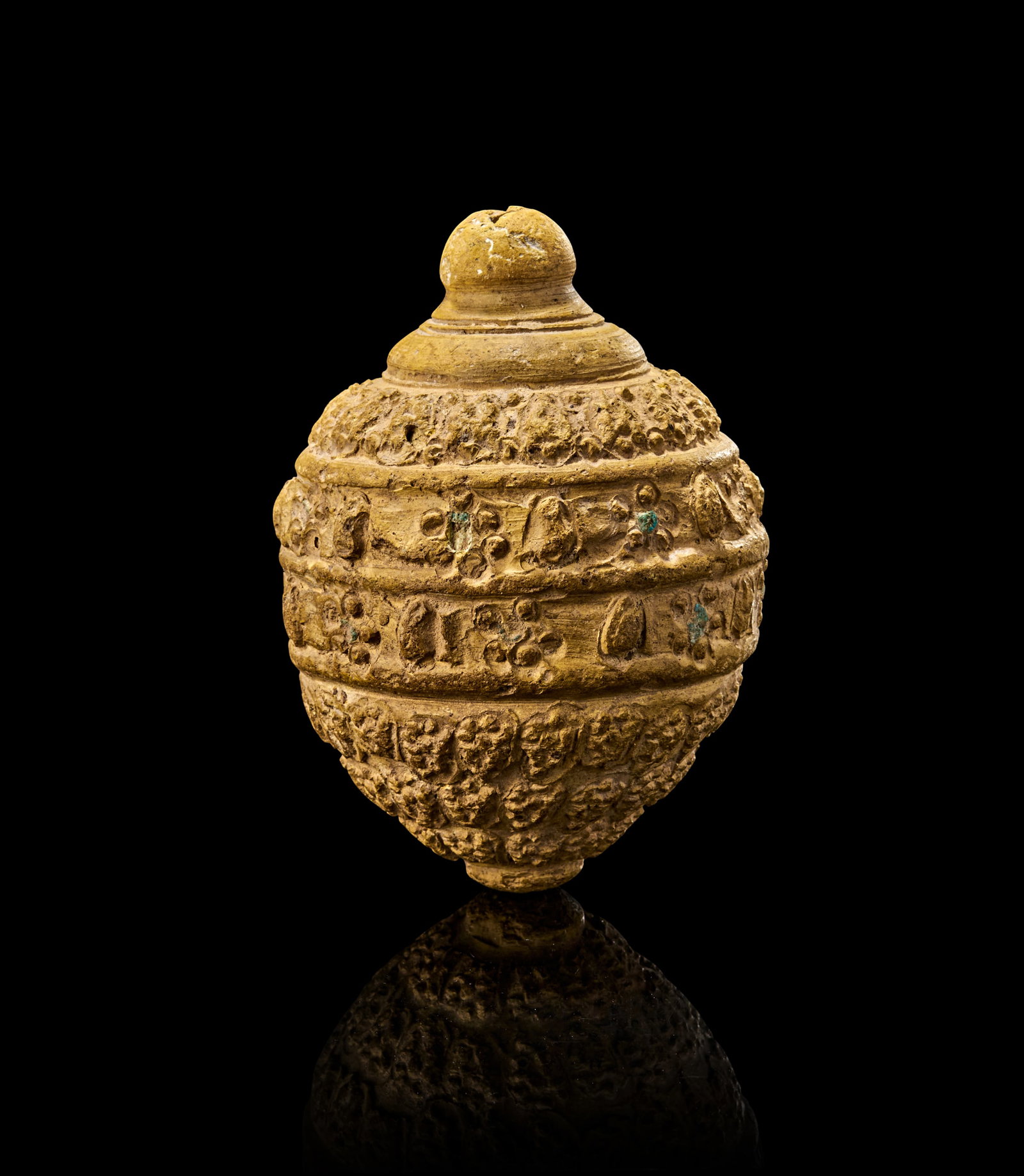 A RARE SELJUK POTTERY CONICAL FLASK/HAND GRENADE, PERSIA, 12TH - 13TH CENTURY: Shaped in a robust conical form with a rounded body and tapering spout, the surface is intricately moulded with decorative bands of floral and geometric motifs in relief, interspersed with occasional