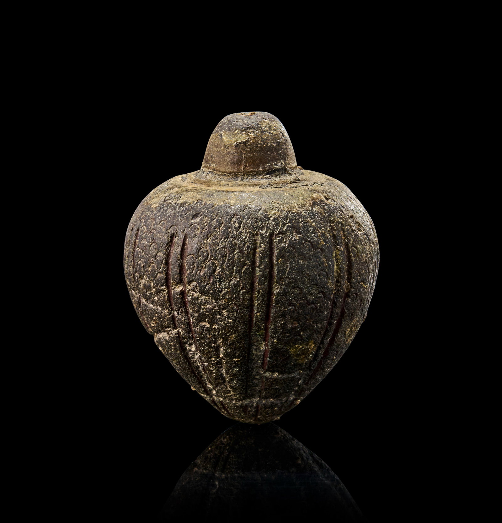 A RARE MAMLUK POTTERY CONICAL FLASK/HAND GRENADE, EGYPT OR SYRIA, 13TH - 14TH CENTURY: This ovoid vessel is formed with a pointed base and a short neck featuring a narrow opening. The body is richly decorated with carved vertical ribs and textured surface motifs. These vessels were beli
