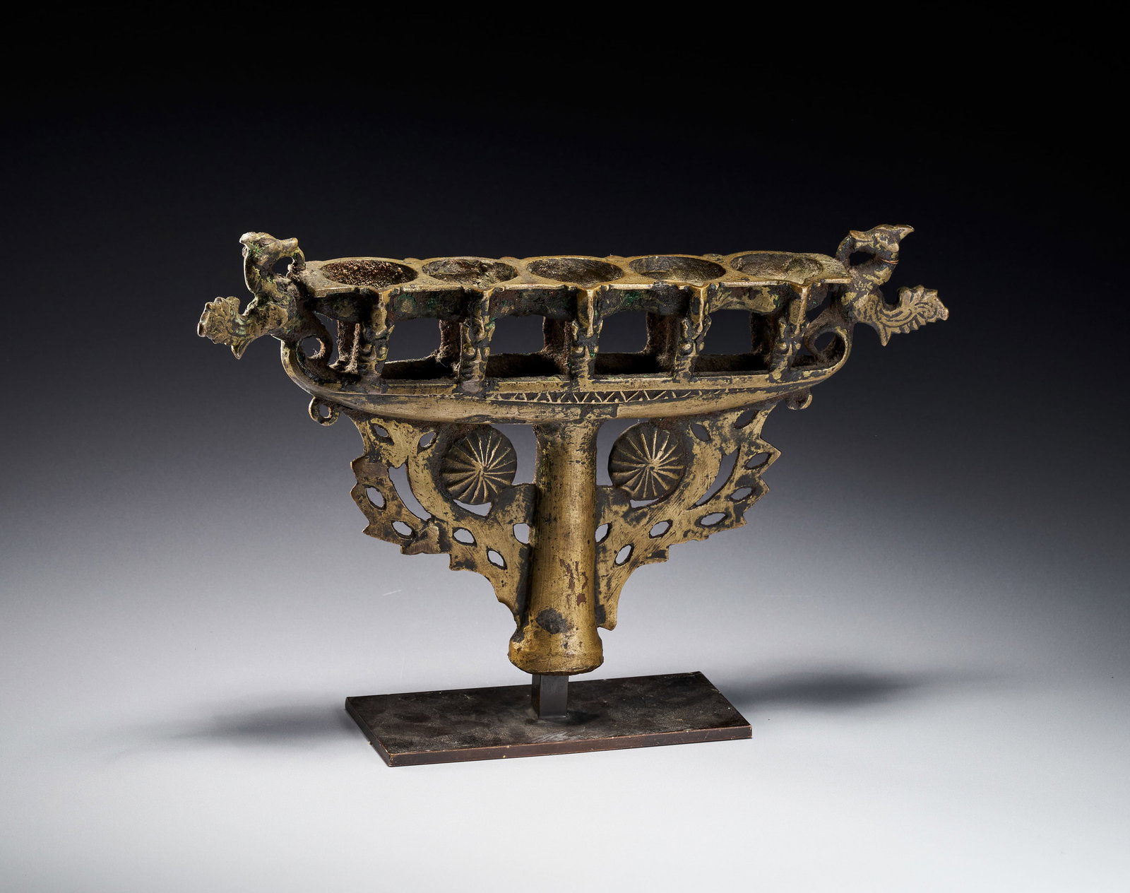 A SOUTH INDIAN DECCANI BRONZE BOAT LAMP, 17TH - 18TH CENTURY: This cast bronze oil lamp, originating from the Deccani or Kerala region of South India, dates to the 17th or 18th century and is sourced from a private French collection. The lamp features a horizont