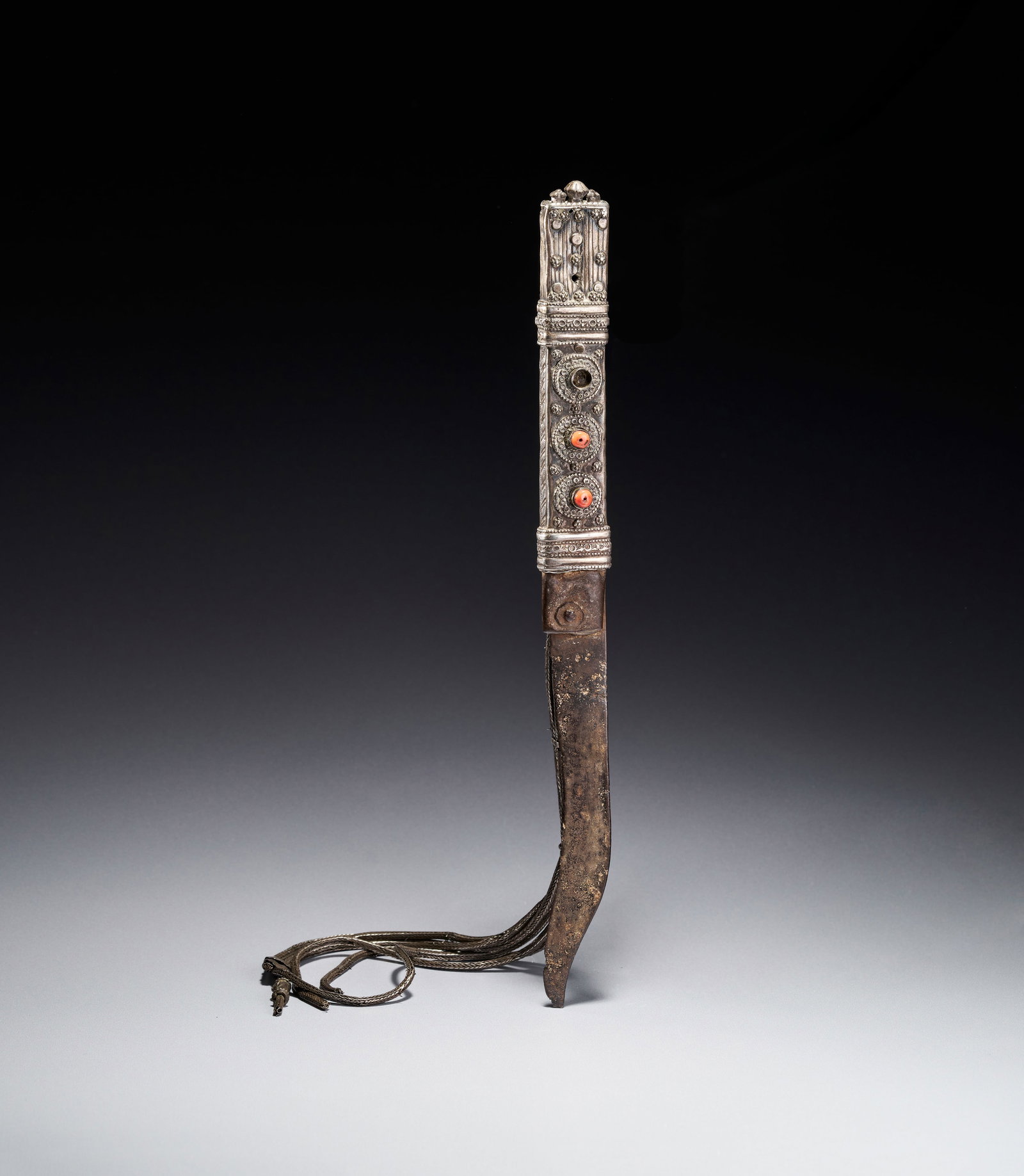 A BEDOUIN SHIBRIYA DAGGER WITH FILIGREE WHITE METAL AND CORAL BEADS, 19TH CENTURY: This antique Bedouin shibriya dagger is a traditional weapon and status symbol from the Levant and Arabian Peninsula, dating to the late 19th or early 20th century. The weapon features a single-edged