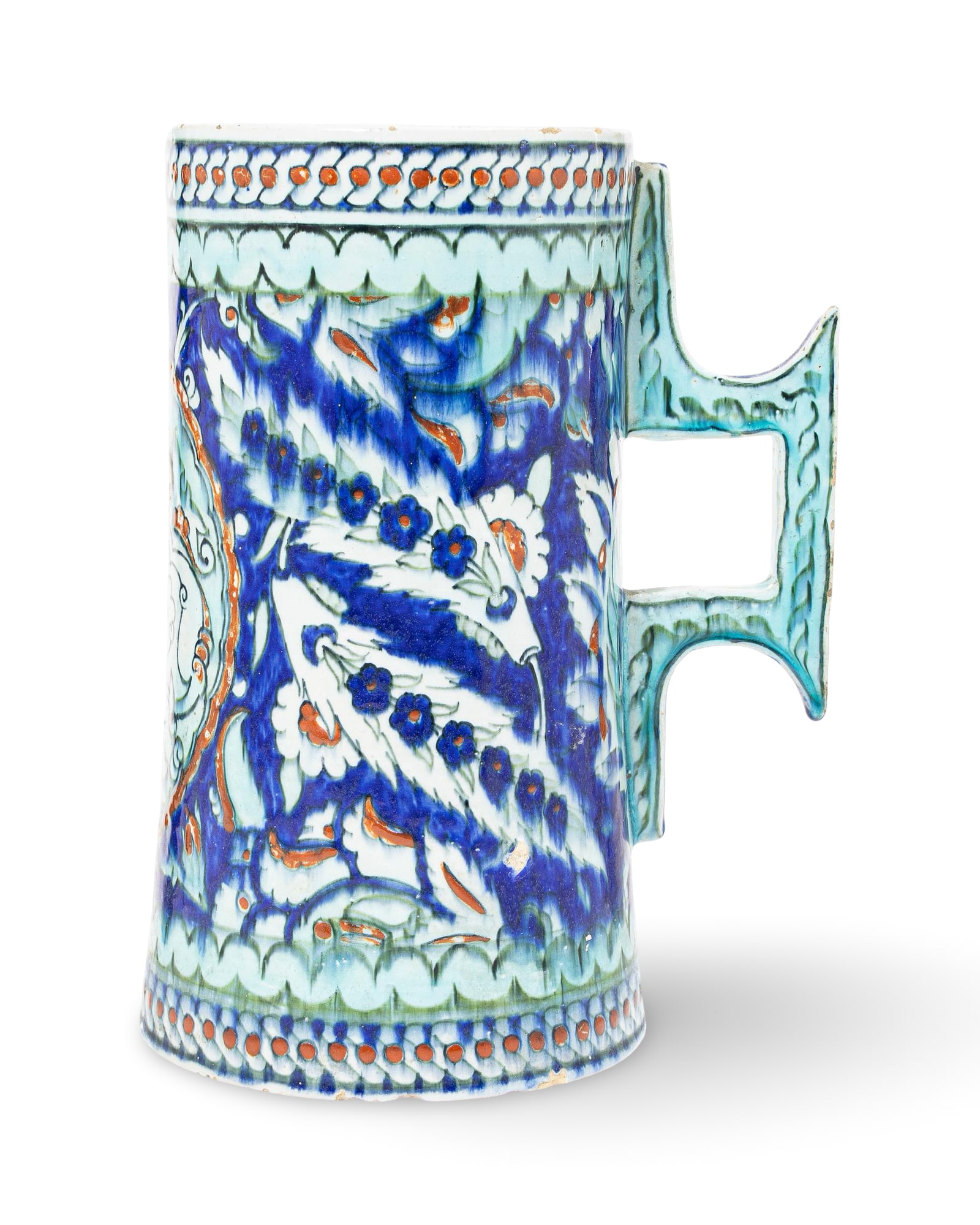 A LARGE IZNIK STYLE CANTAGALLI POTTERY TANKARD, 19TH CENTURY: The vessel is decorated in cobalt blue, turquoise, and raised red enamels on a white ground, featuring traditional Ottoman motifs such as serrated Saz leaves, floral rosettes, and a large foliate meda