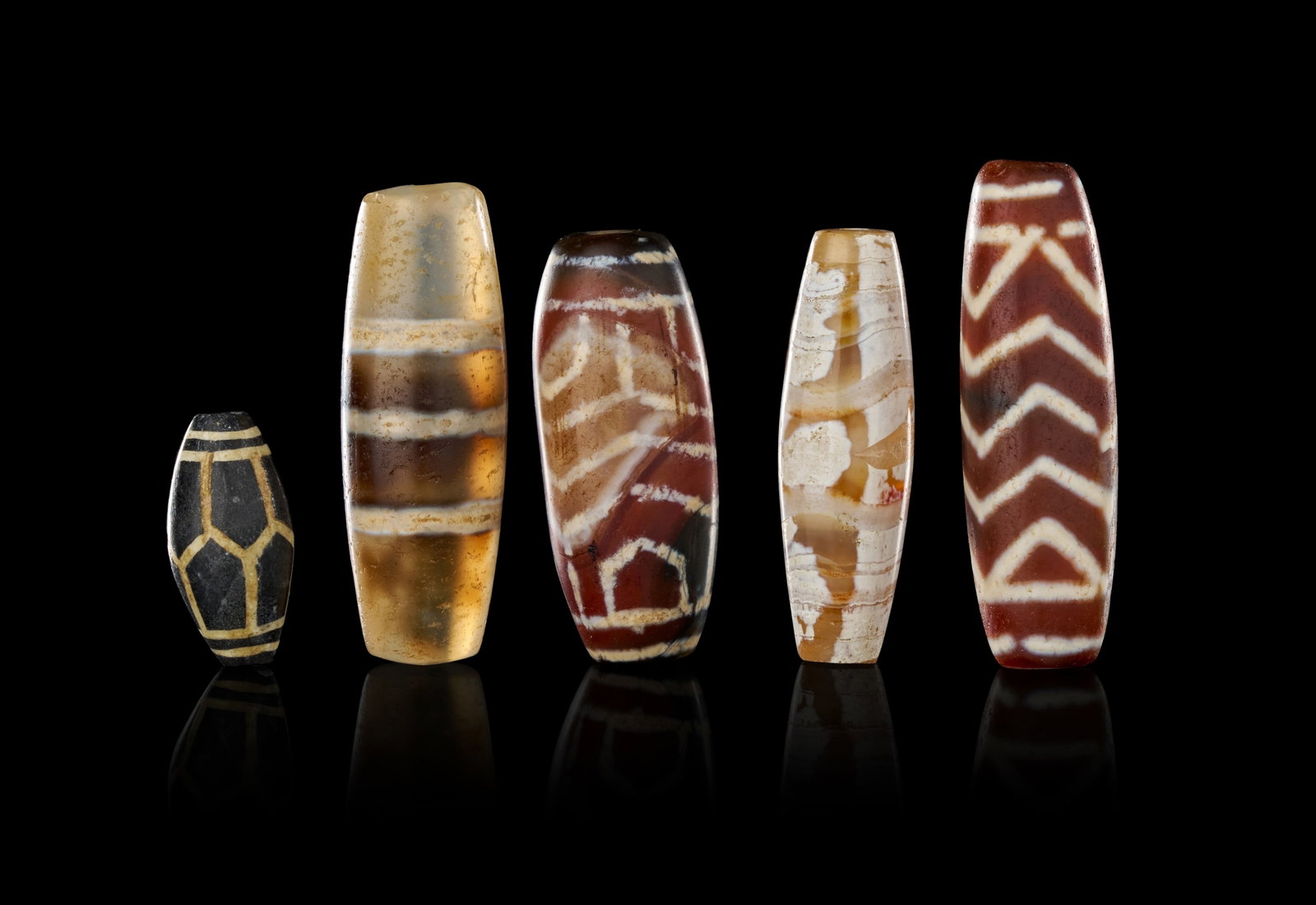 A GROUP OF ANCIENT HIMALAYAN AND CENTRAL ASIAN ETCHED AGATE BEADS: A group of ancient alkali-etched agate beads, historically associated with the Himalayan region and Central Asia. This collection includes various forms such as barrel, tapered barrel, and biconical s