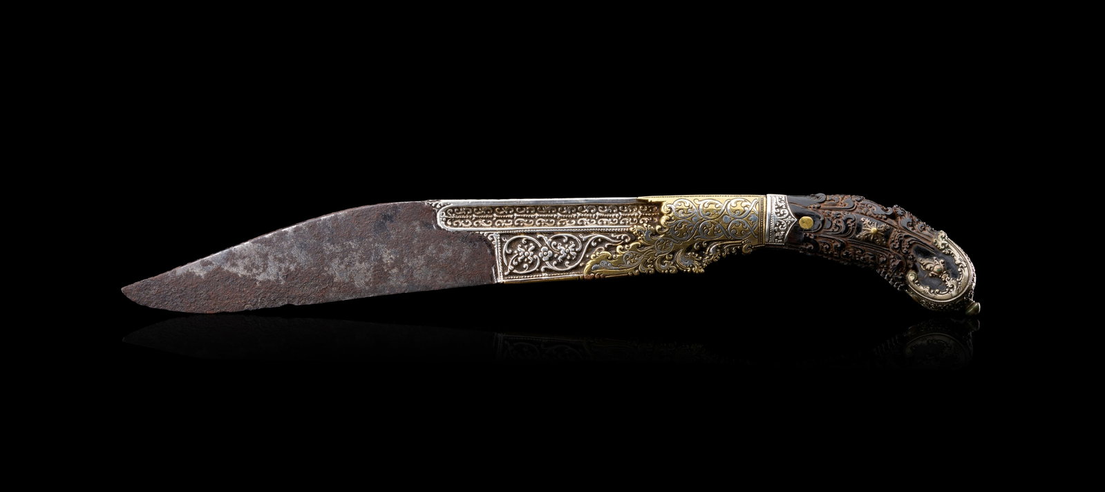 A SRI LANKAN PIHA-KAETTA DAGGER WITH BRASS & SILVER MOUNTS, 18TH CENTURY: A Sri Lankan piha kaetta dagger, dating from the 18th or early 19th-century Kandy period, featuring a heavy steel blade with a recurved profile. The base of the blade and the bolster are decorated wit