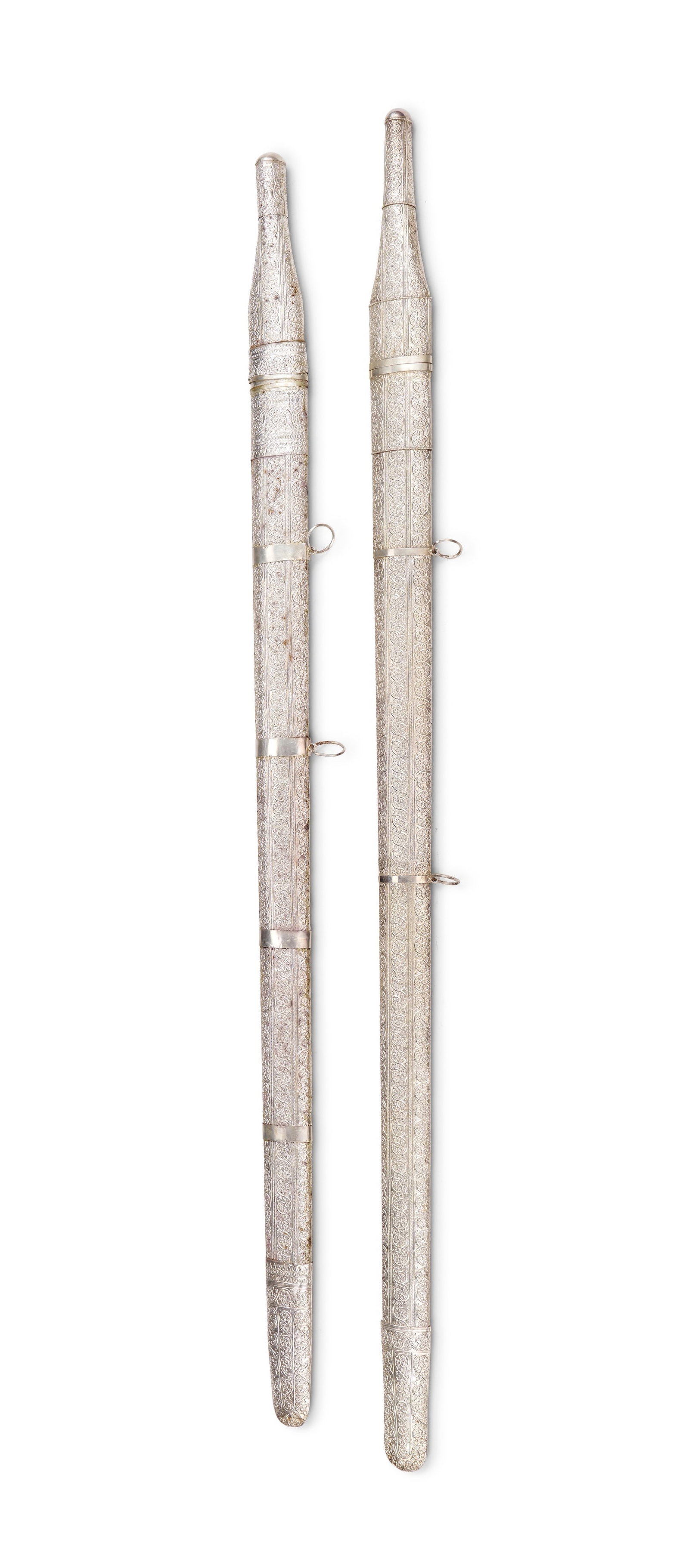 A PAIR OF OMANI WHITE METAL PRESENTATION SWORDS IN A FITTED WOODEN CASE, 20TH CENTURY: A matched pair of mid-20th century Omani white metal presentation swords, traditionally known as Saif, complete with their original fitted presentation case. Each sword features a straight, single-edg