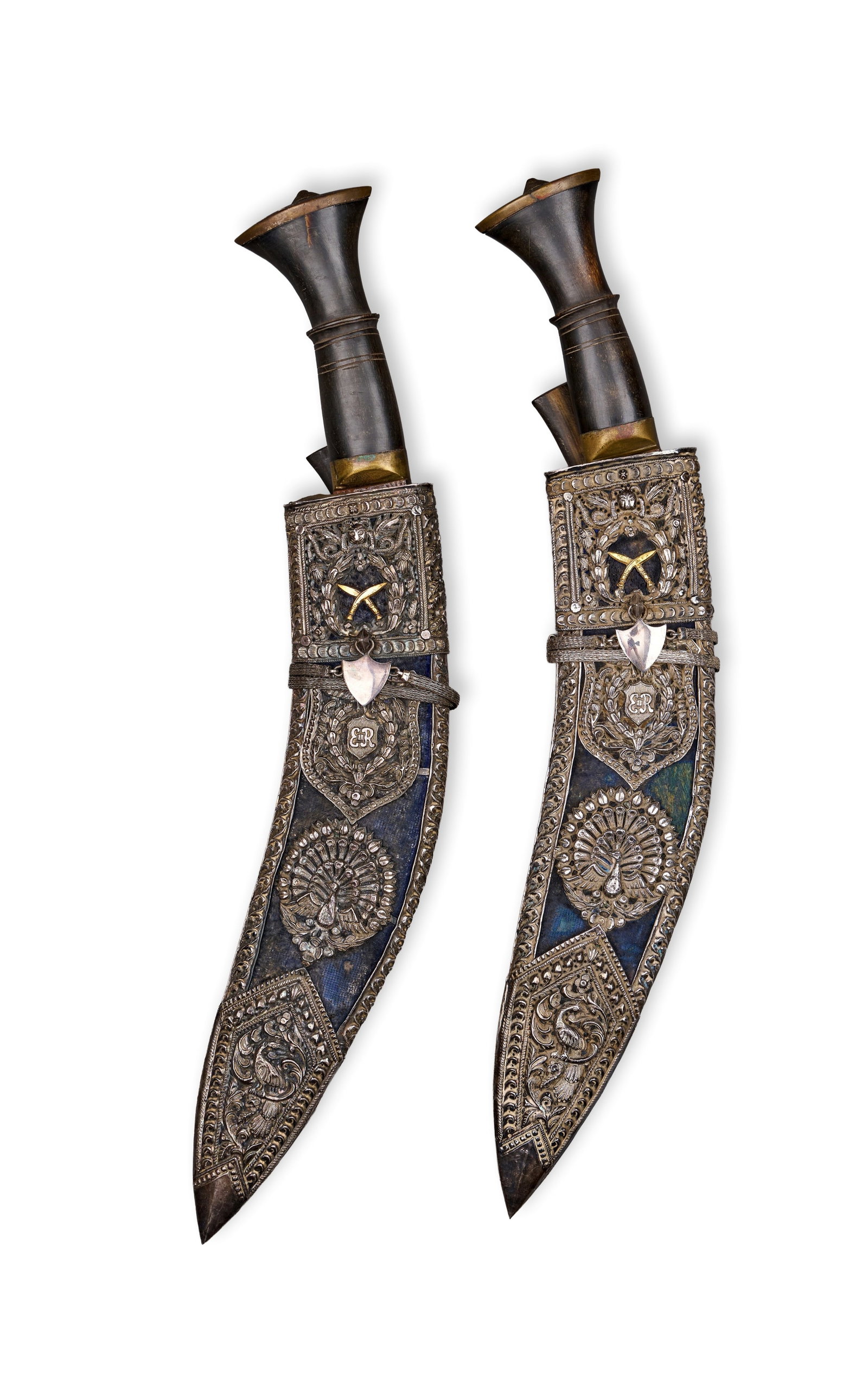 A PAIR NEPALESE SILVER-MOUNTED KOTHIMORA KHUKRIS DAGGERS,OF BRITISH RAJ PERIOD DEHRA DUN, 19TH: A matching pair of silver-mounted Nepalese Kothimora khukris produced in Dehra Dun, India, during the British Raj period. Each weapon features a traditional forward-curving steel blade with a single e