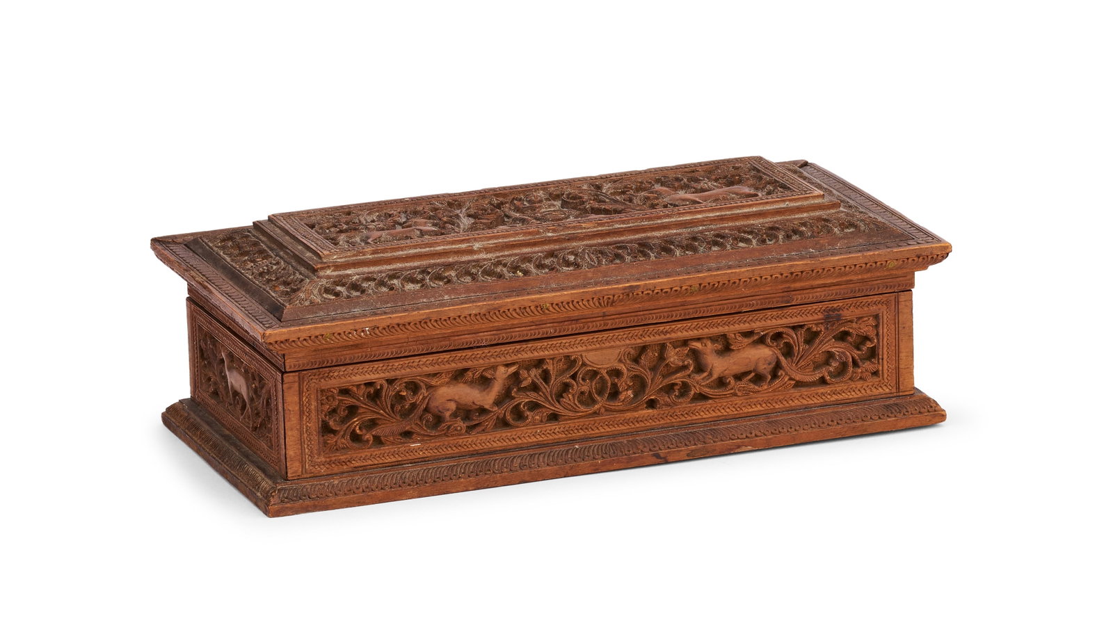 AN INDIAN CARVED SANDALWOOD BOX WITH ANIMALS AND FOLIATE SCROLLS, 19TH CENTURY: An Indian rectangular box of fine-grained, light-toned wood, identified as sandalwood, featuring dense high-relief carving across all exterior surfaces. The decorative scheme consists of stylized quad