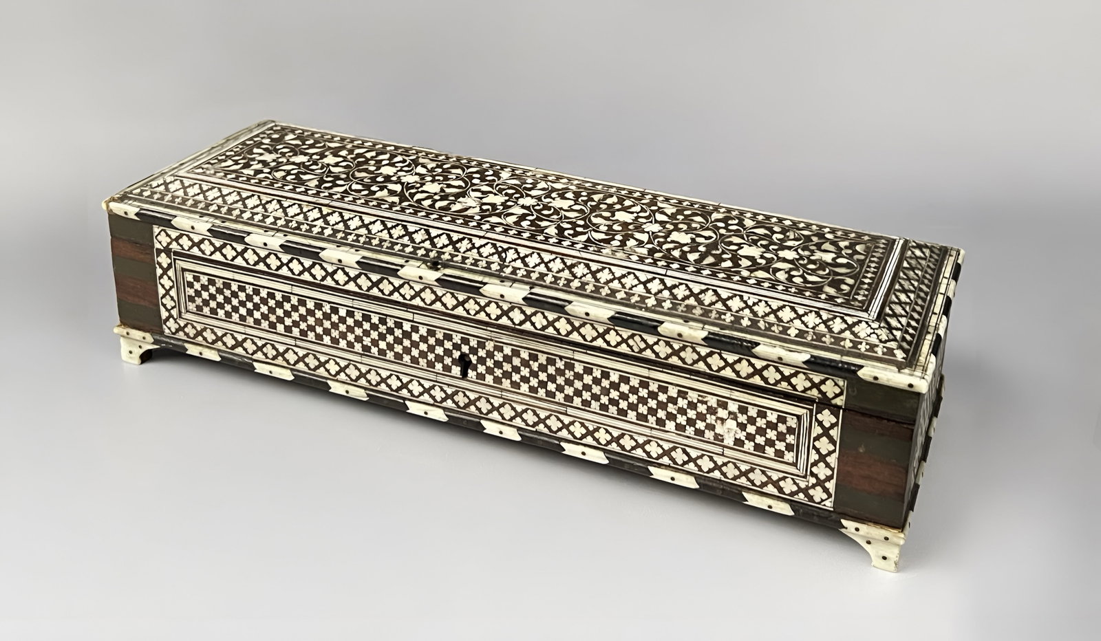 AN ANGLO-INDIAN VIZAGAPATAM INLAID ROSEWOOD BOX, 19TH CENTURY: A nineteenth-century Anglo-Indian Vizagapatam rosewood box of rectangular form. The exterior is extensively decorated with intricate bone or ivory inlay. The hinged lid features a central panel of scr