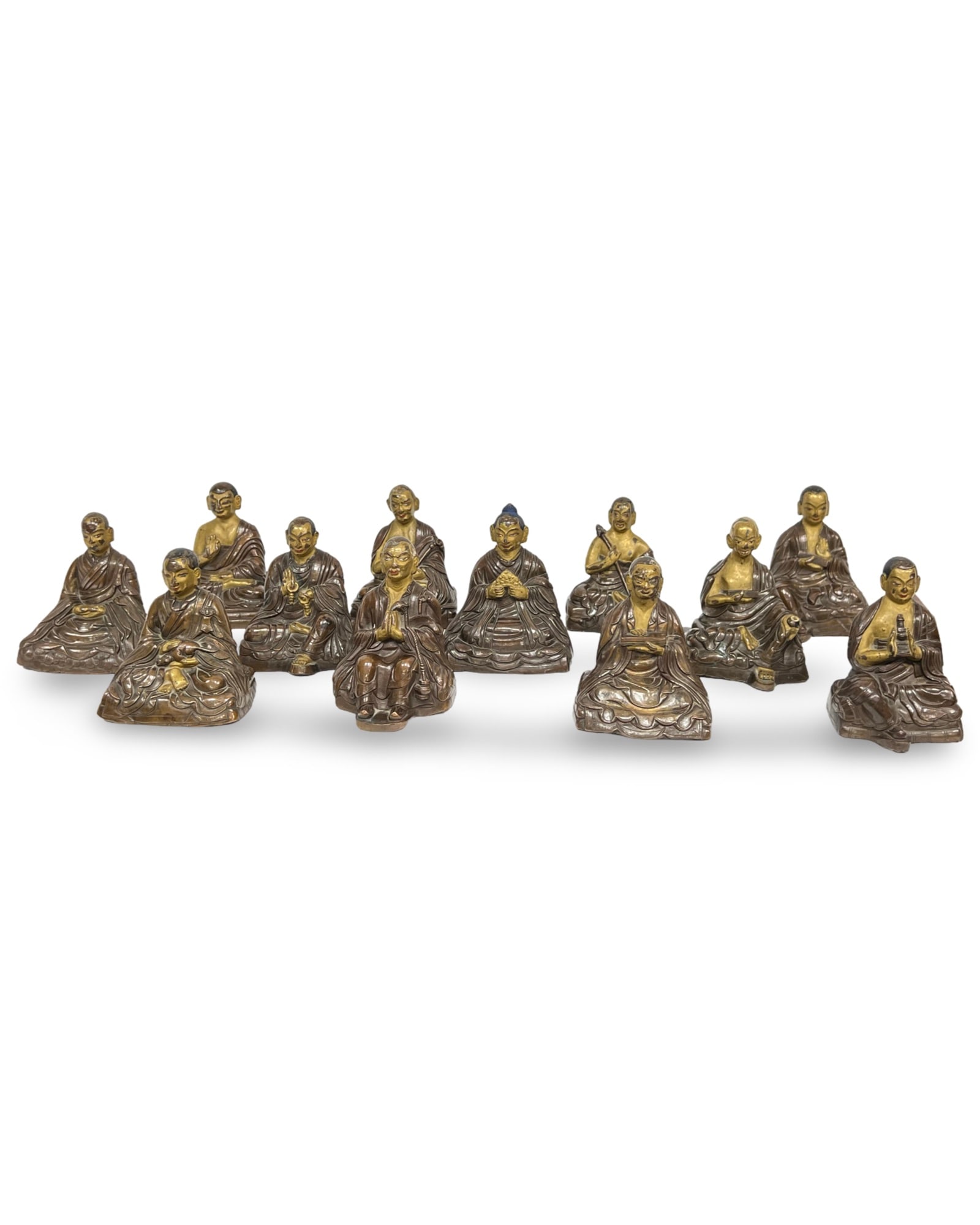 A SET OF TWELVE SINO-TIBETAN PARCEL-GILT BRONZE FIGURES OF ARHATS, 18TH CENTURY: A set of twelve Tibetan cast bronze figures of Arhats, dating to the 18th century. Each figure is depicted seated in a variety of expressive poses on rectangular or irregular rockwork-style bases. The