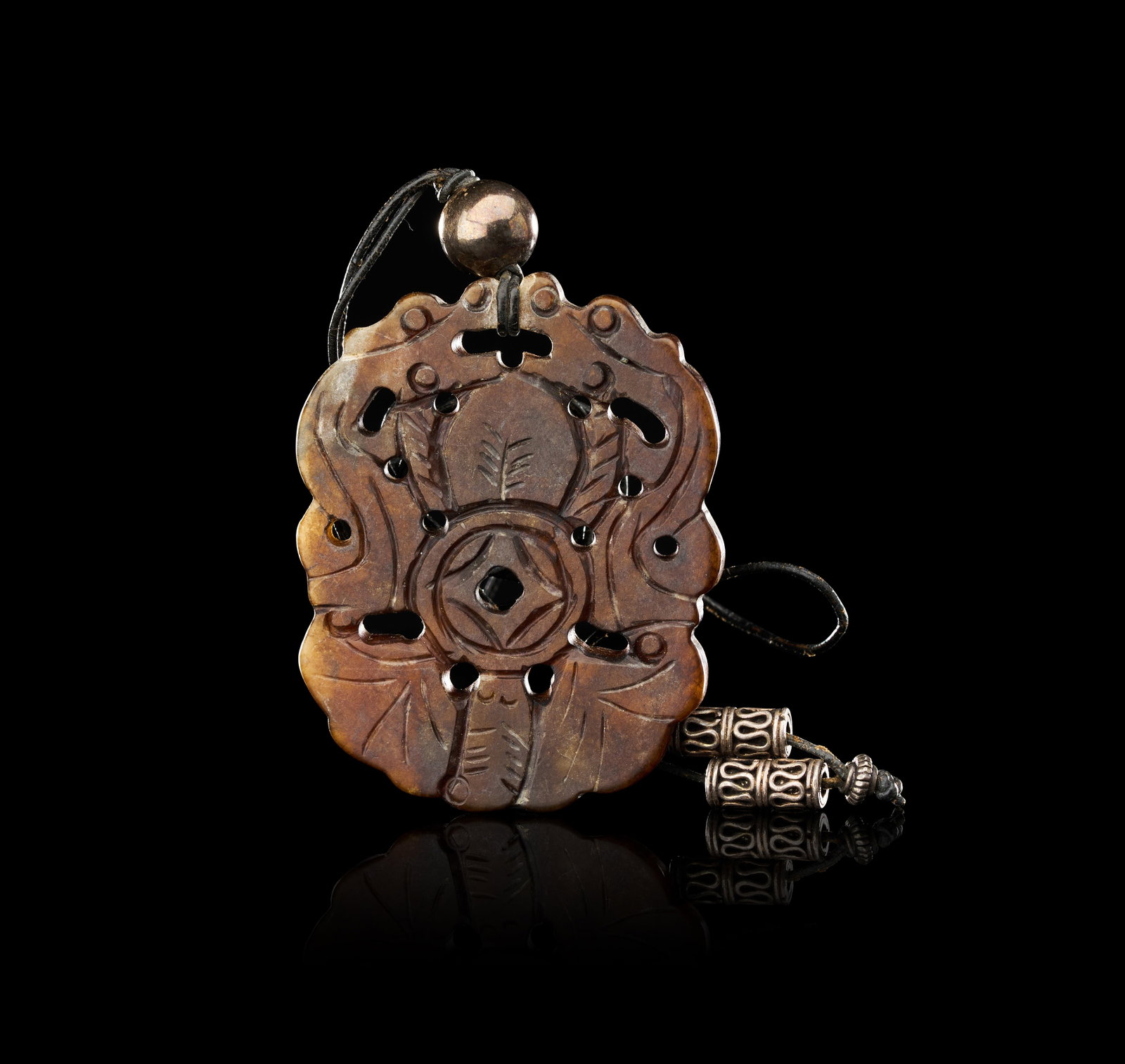 A CARVED RUSSET NEPHRITE JADE PENDANT WITH CENTRAL CASH COIN MOTIF AND FILIGREE METAL BEADS: This lot comprises a lobed, scalloped plaque of russet-coloured nephrite jade, featuring a combination of openwork and incised carving. The central motif depicts a traditional Chinese cash coin, repre