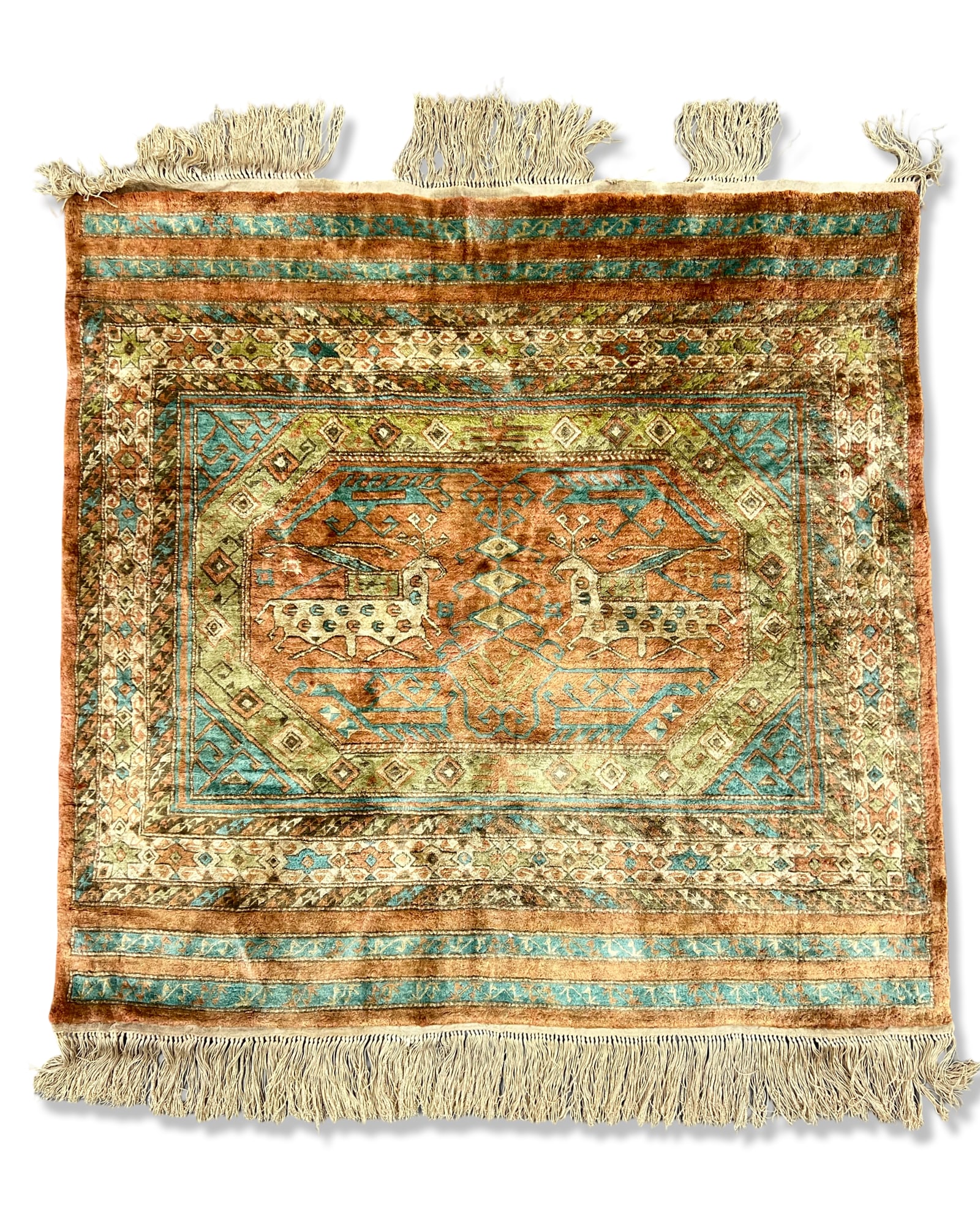 A HAND-KNOTTED PERSIAN SILK RUG WITH CENTRAL ZOOMORPHIC MEDALLION: A hand-knotted silk rug featuring a terracotta-coloured central field decorated with two mirrored stylised zoomorphic figures. The figures appear as stags or deer with spotted bodies and prominent ant