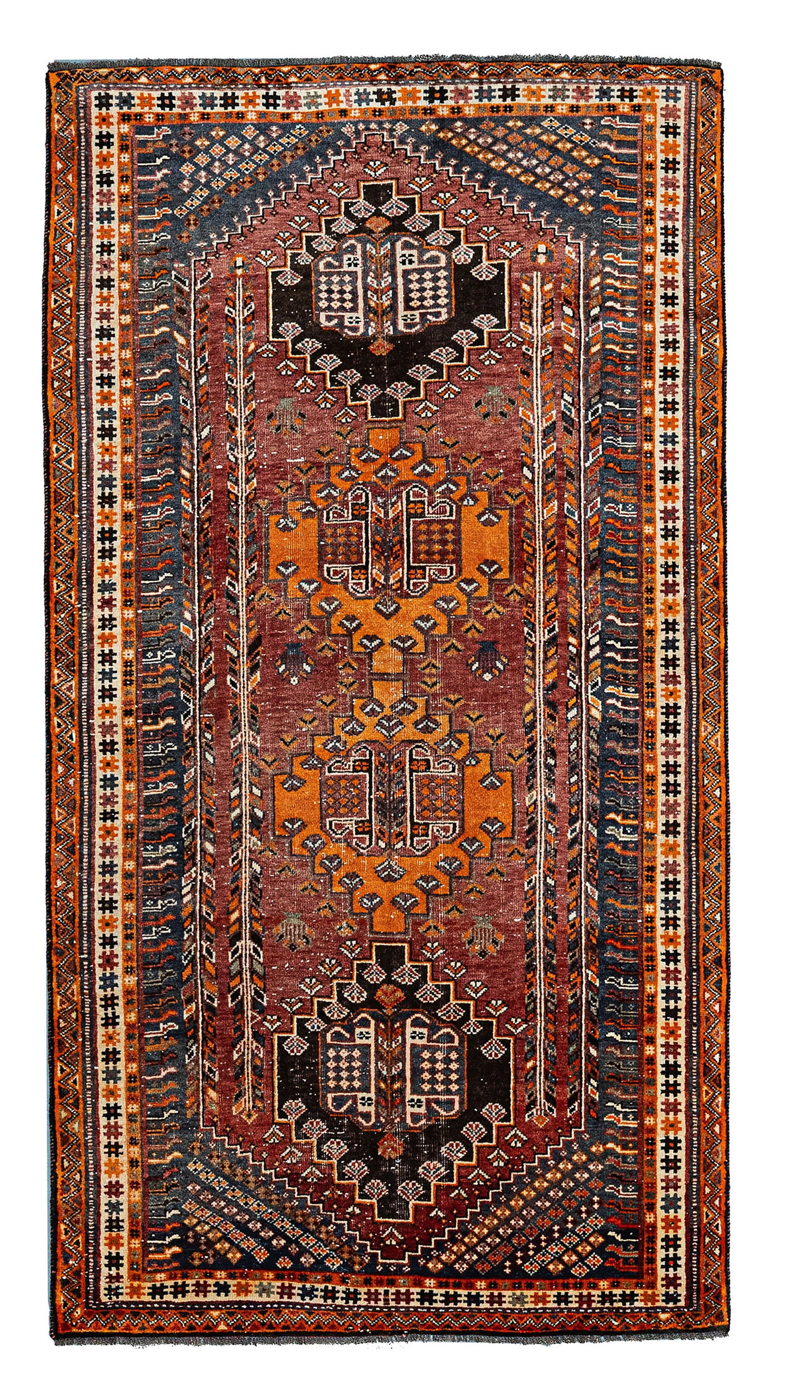 A QASHQAI HAND-KNOTTED WOOL TRIBAL RUG, SOUTHWEST PERSIA, CIRCA 1920: A hand-knotted wool pile Qashqai rug on a wool foundation, originating from Southwest Persia. The design features a dark madder-red field containing four vertically arranged, stepped hexagonal medalli