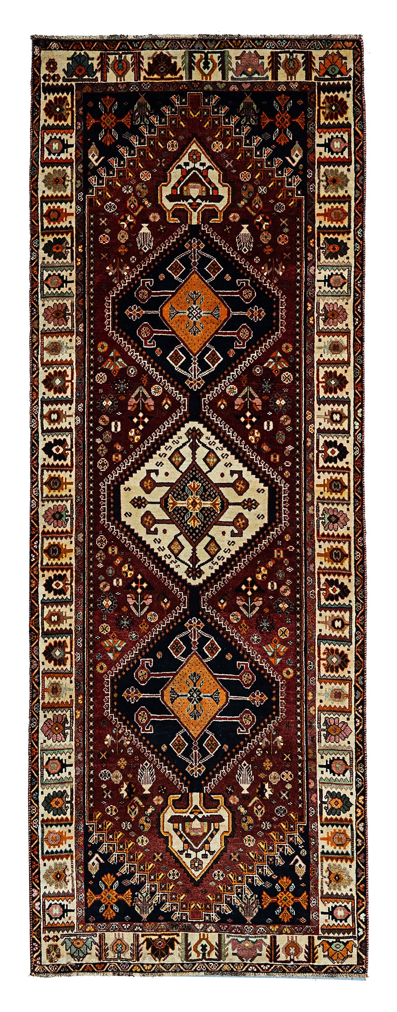 A PERSIAN QASHQAI TRIBAL RUNNER, CIRCA 1980S: A hand-knotted wool runner of Qashqai tribal design, Southwest Persia, dating to circa 1980s. The long-format piece features a classic triple medallion layout arranged vertically on a deep madder red 