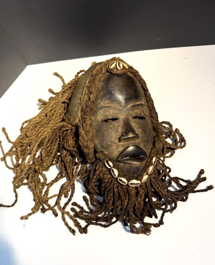 VINTAGE DAN MASK FROM IVORY COAST OF AFRICA: All hand made ceremonial mask, with age wear, made of hardwood, adorned with cowrie shells on a heavy rolled textured fabric. these were integral to rituals an ceremonies about 10"