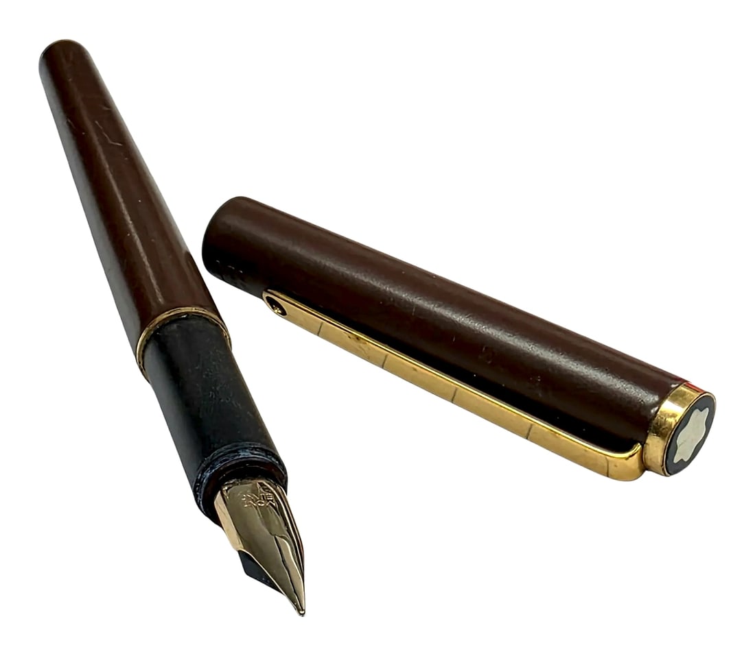 Montblanc Brown Fountain Pen with Gold-Tone Trim: A Montblanc fountain pen featuring a dark brown cap and barrel, a black grip section, and gold-tone hardware. The cap is fitted with a flat black finial inset with the Montblanc white star emblem, a g