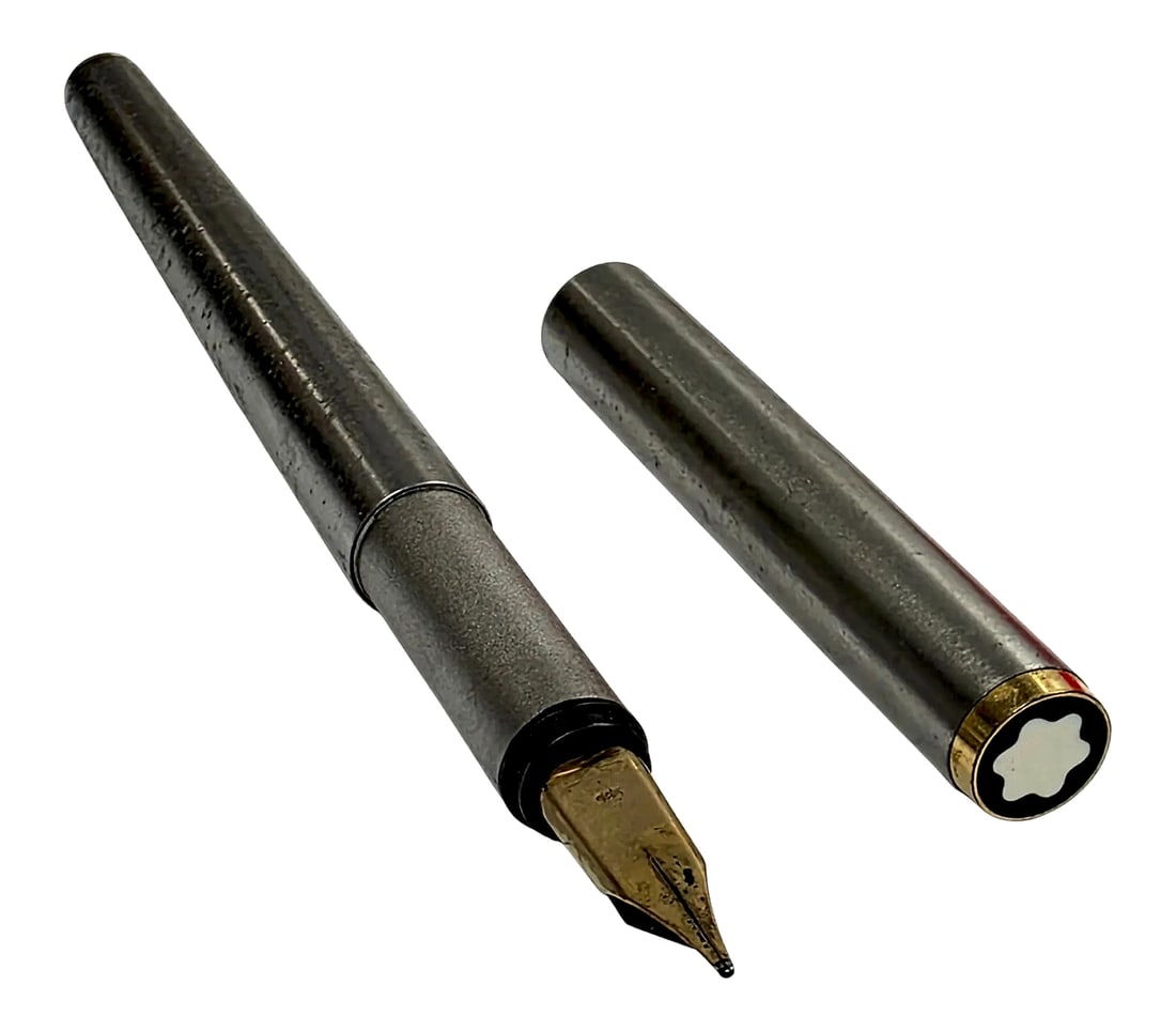 Montblanc Noblesse Fountain Pen with 14K Gold Nib: A Montblanc Noblesse cartridge/converter fountain pen featuring a dark textured metallic-tone barrel and cap, gold-tone trim, and the iconic white Montblanc snowcap emblem on the cap end. The pen is f