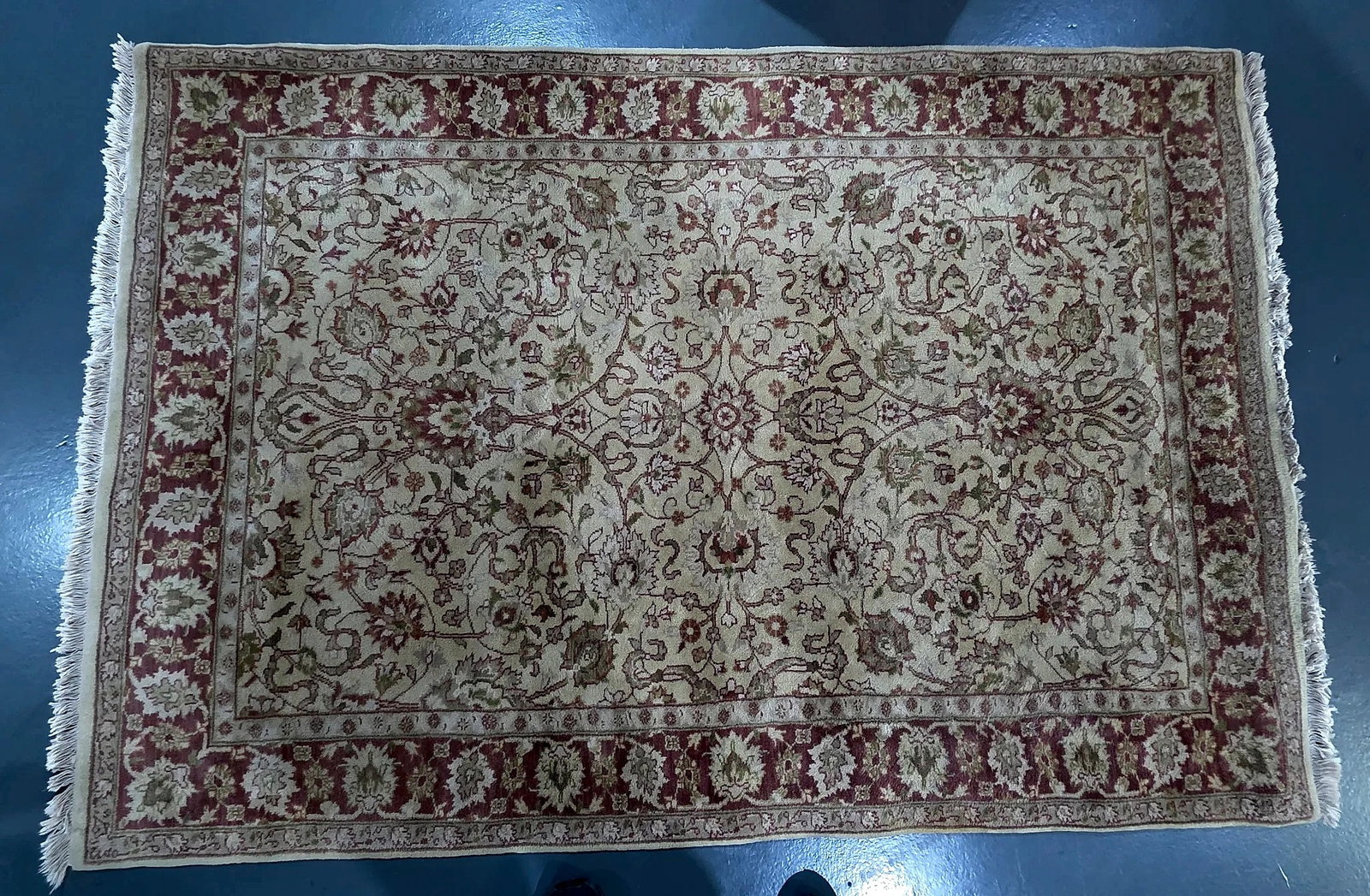 Traditional Oriental Style Ivory and Burgundy Floral Pattern Area Rug: A traditional Persian-inspired rectangular area rug featuring a central ivory-tone field decorated with an allover repeating floral vine and palmette arabesque motif in muted green, tan, and burgundy