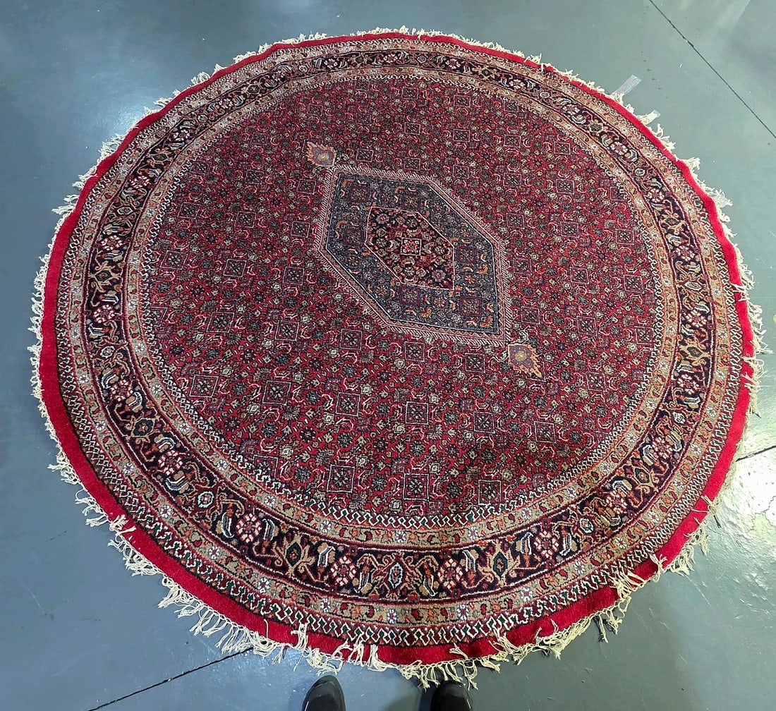 Khurram Carpets Limited Bhadohi Round Patterned Fringe Rug: A circular area rug featuring a traditional Oriental-style design, produced by Khurram Carpets Limited in Bhadohi, Uttar Pradesh, India. The underside retains the manufacturer's original cloth label. 